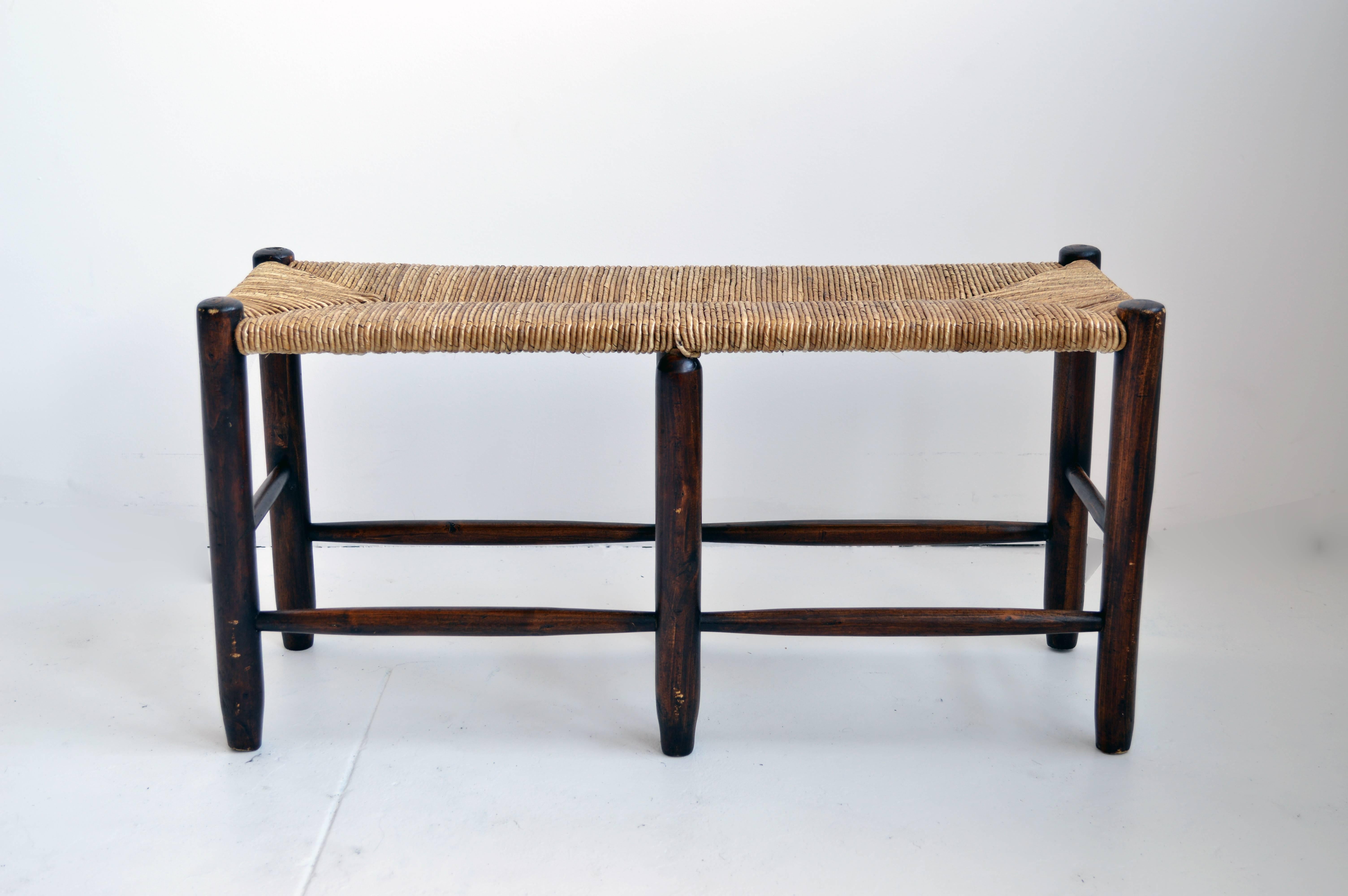 This six-legged wooden bench with woven rush seat. Originally from France, unknown date of manufacture.