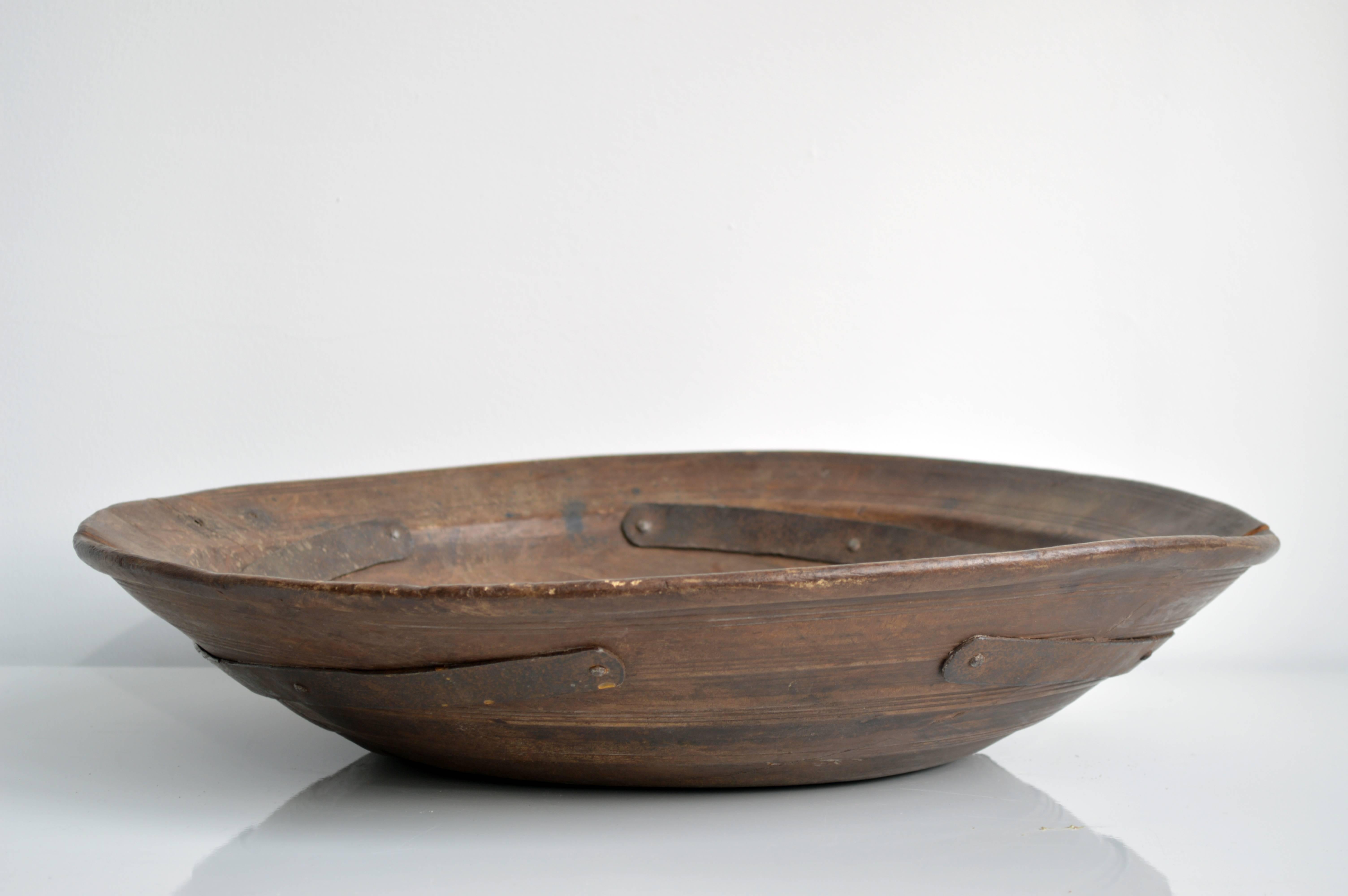 Rustic carved wood bowl, originally from Iran. This piece would make for a beautiful decorative display vessel in any home. The bowl has some cracks, secured by metal supports.