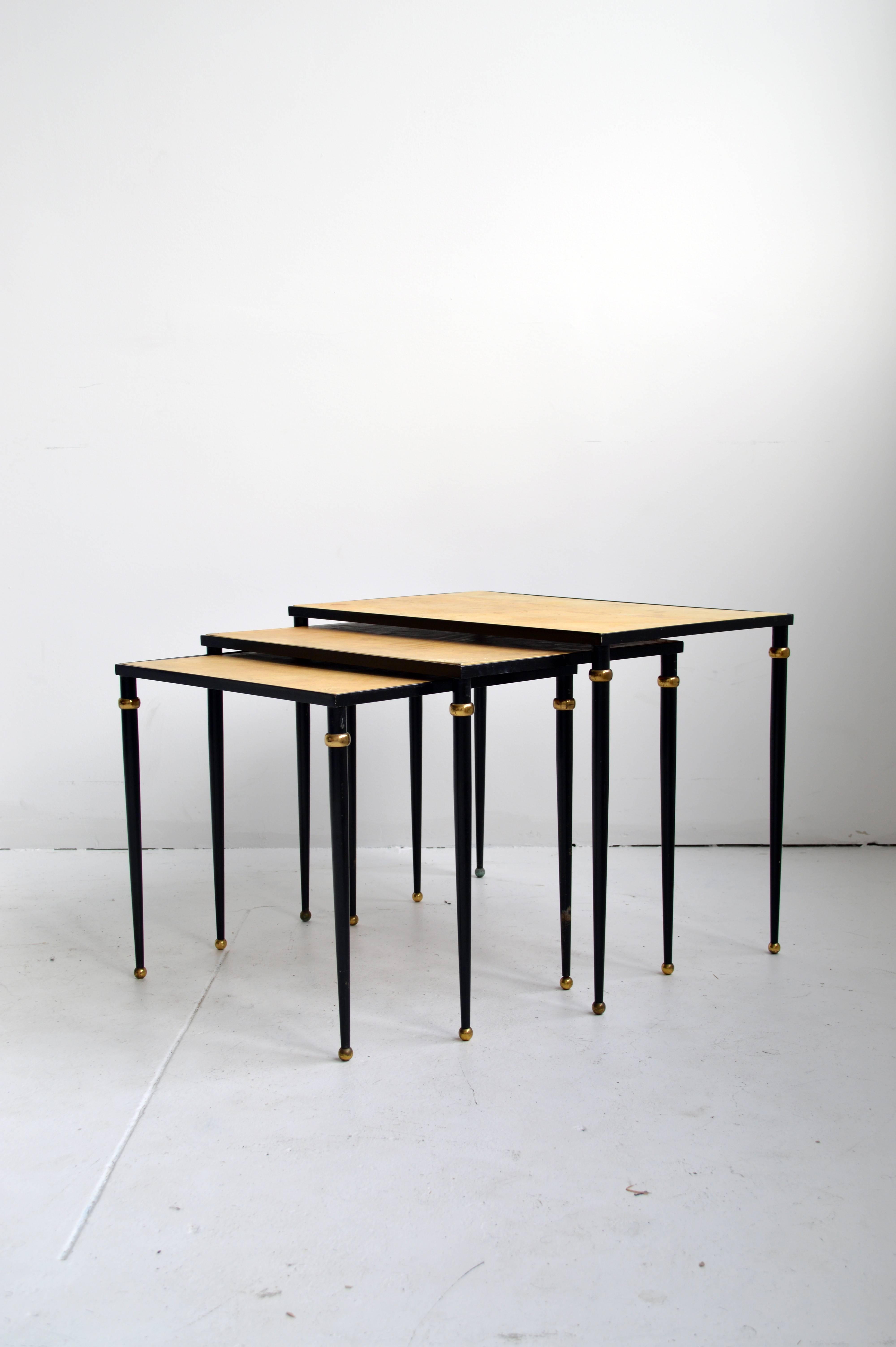 Three nesting tables with dark metal frame with brass details and inset parchment tops. Largest nesting table is missing one brass ring detail on leg.

Offered by Neal Beckstedt