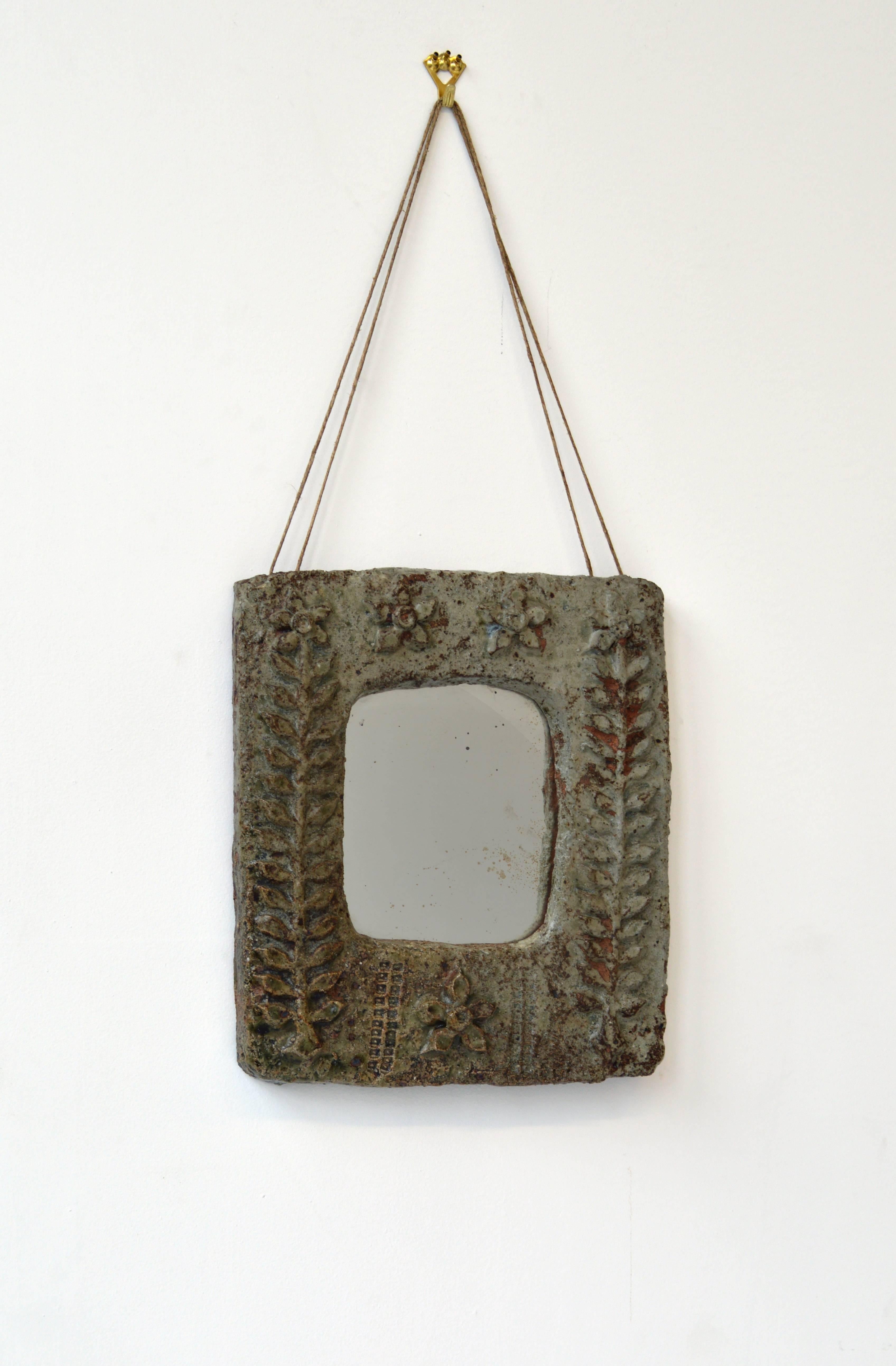 Ceramic wall mirror with relief botanical motif and twine hanging chord. Originally from France, circa 1960. Inset mirror dimensions: 8