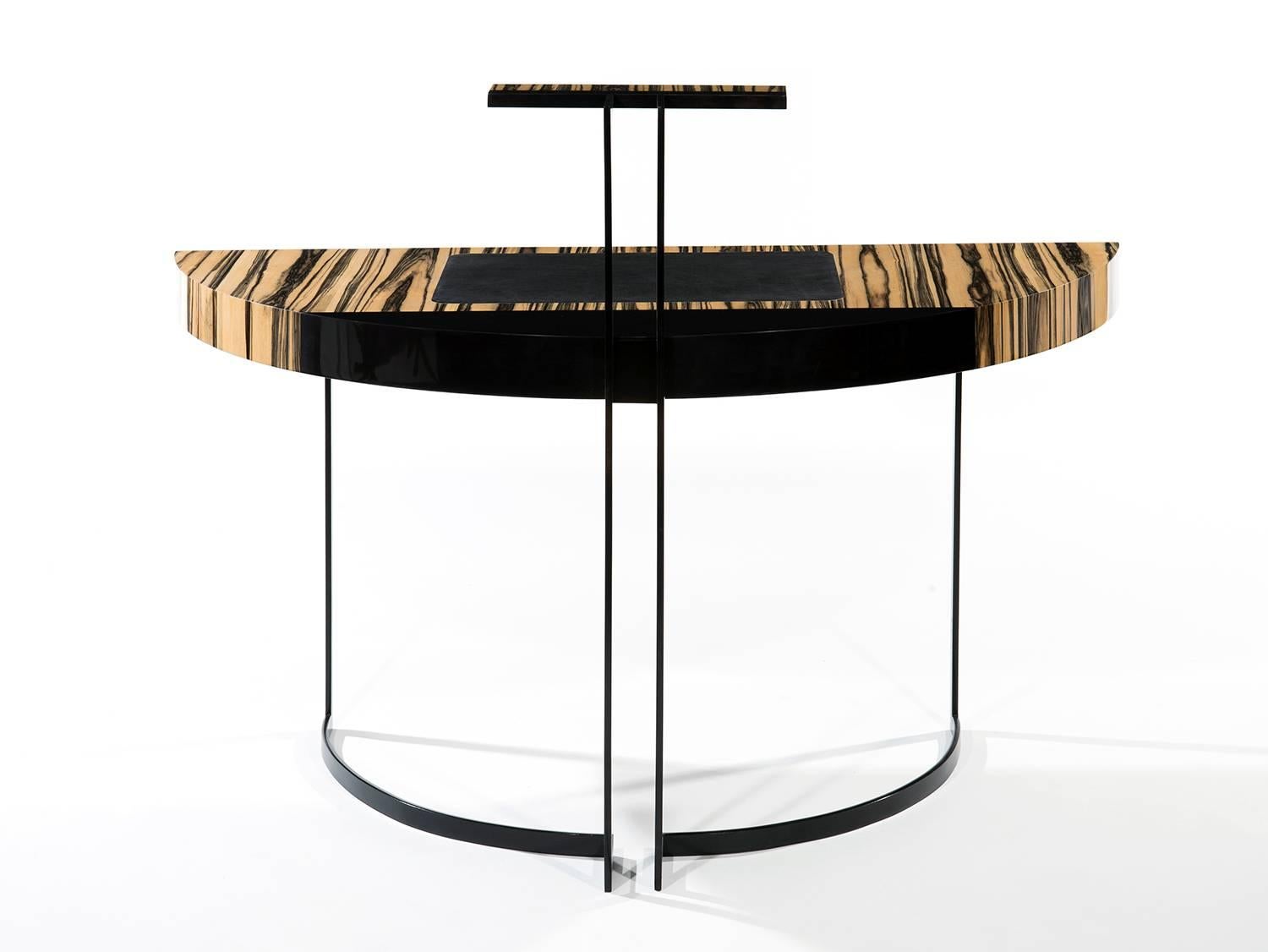 A semicircular black lacquered metal legged desk with a white ebony veneer top and black leather desk blotter. The top of the back legs ends with a led light.

Aymeric Lefort (b. France 1971)
Lefort's decision to become a designer was inspired by