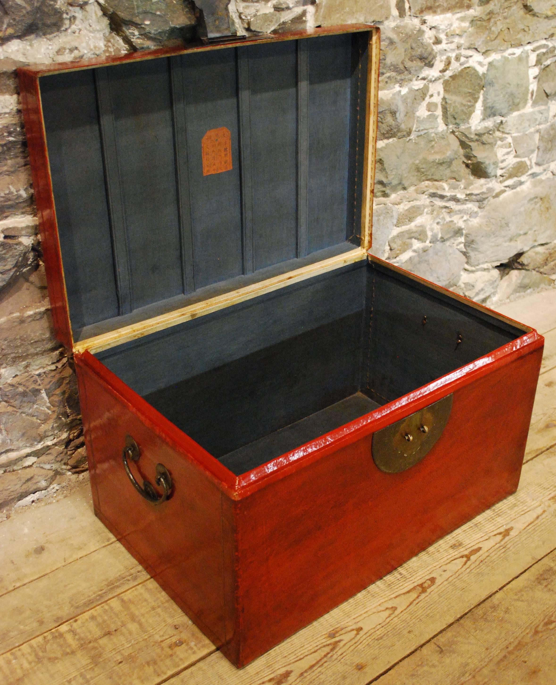 An antique red lacquer leather kimono trunk displaying hand-stitched red leather over camphor wood with multi-layers of rich red lacquers, a blue cloth lining, original hardware and showing the original maker's chop.