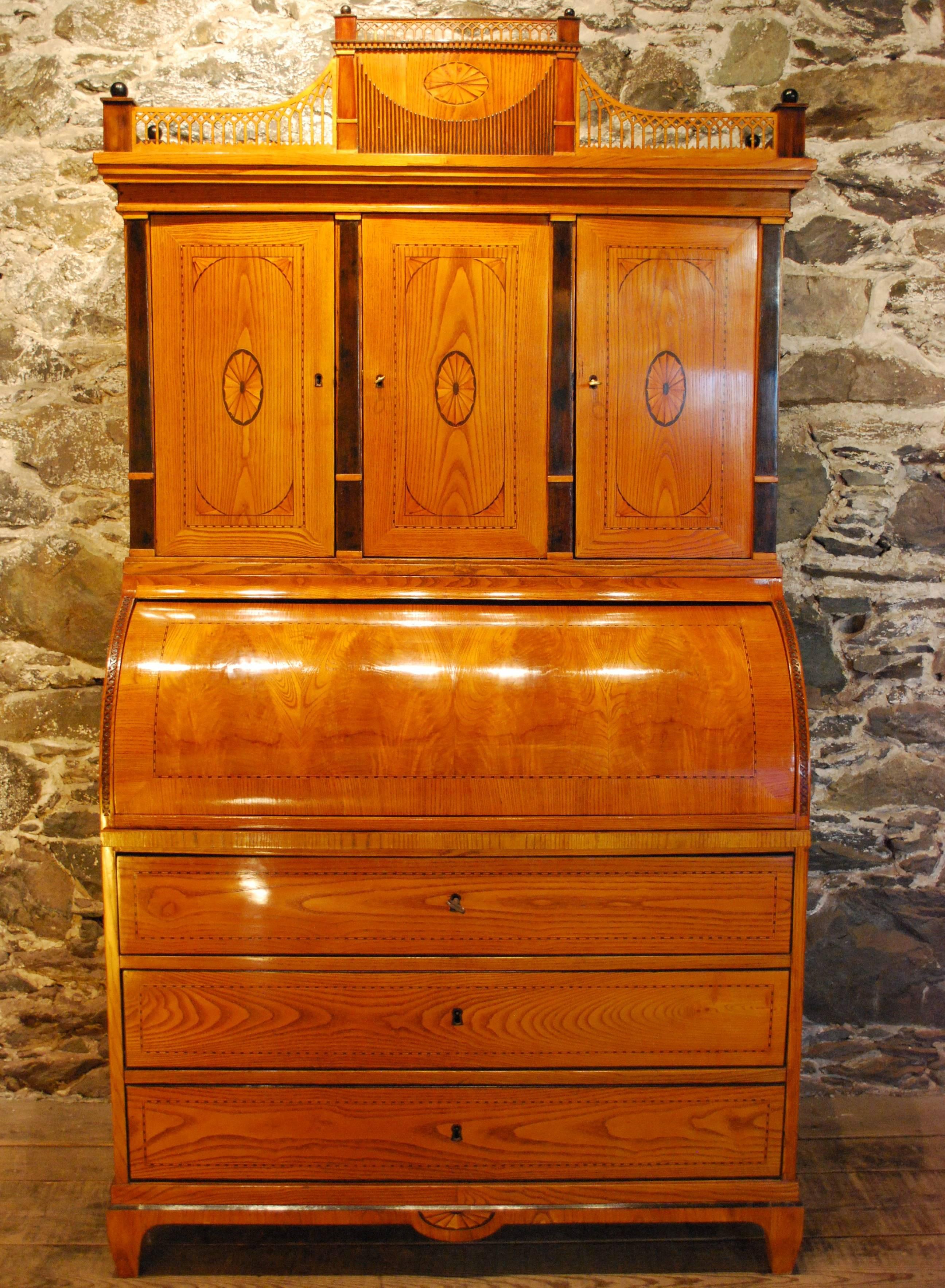 Antique Danish bureau cabinet with a cylinder top connected to its' retractable writing surface. The elm wood acts as a perfect backdrop for the marquetry, inlay and very unusual family profiles all done in a variety of exotic woods.