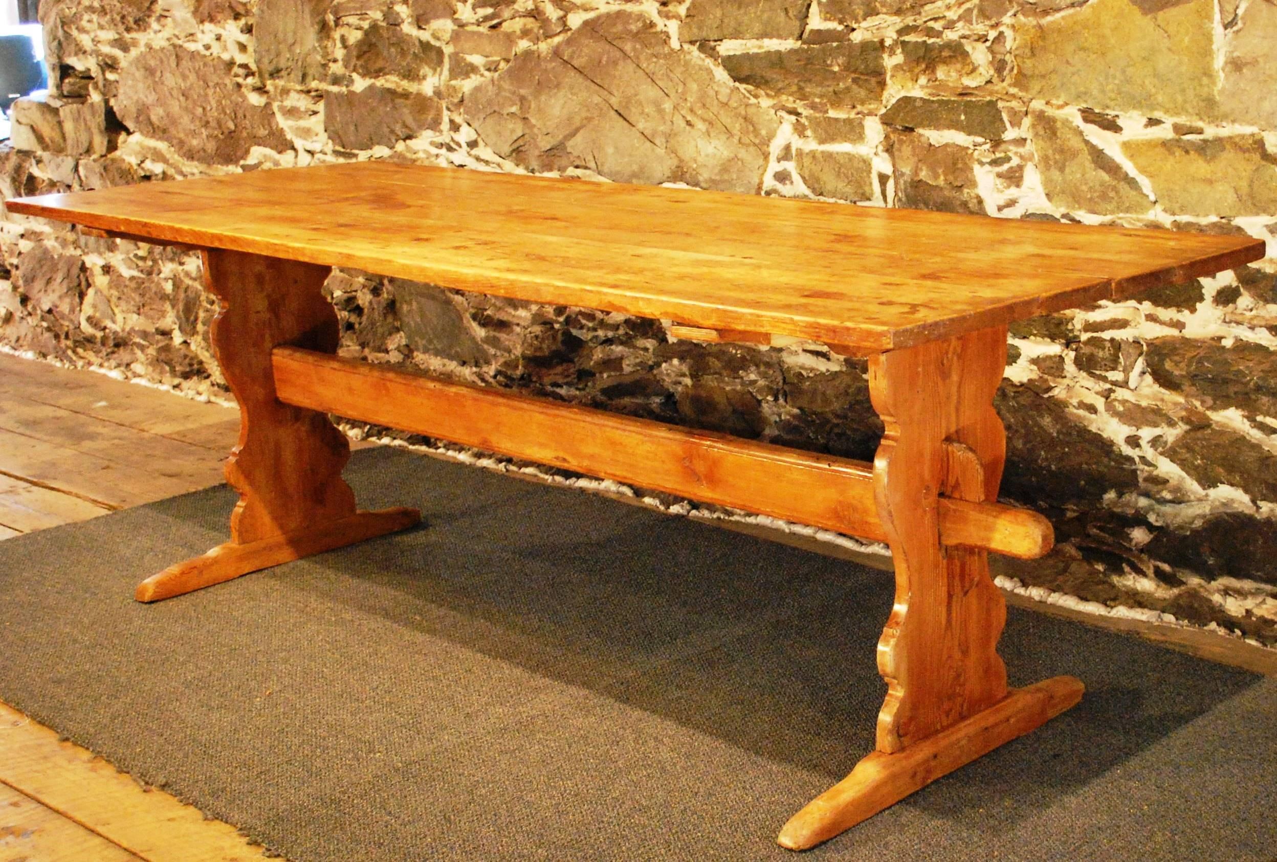 Antique Swedish farm table displaying a wide three board top with a warm aged patina. The strong, finely handcrafted trestle base shows beautifully shaped leg panels and a softly worn rail. This table is very sturdy yet very easy to move.