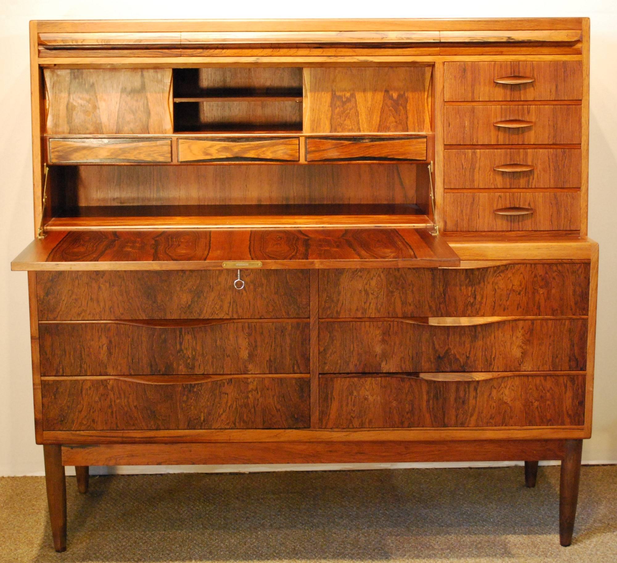An Erling Torvits designed rosewood secretaire produced at Klim Møbelfabrik in the 1960s, this rare Danish Modern secretary desk is crafted from Brazilian rosewood with a locking desk surface that folds down to reveal three bow tie drawers below two