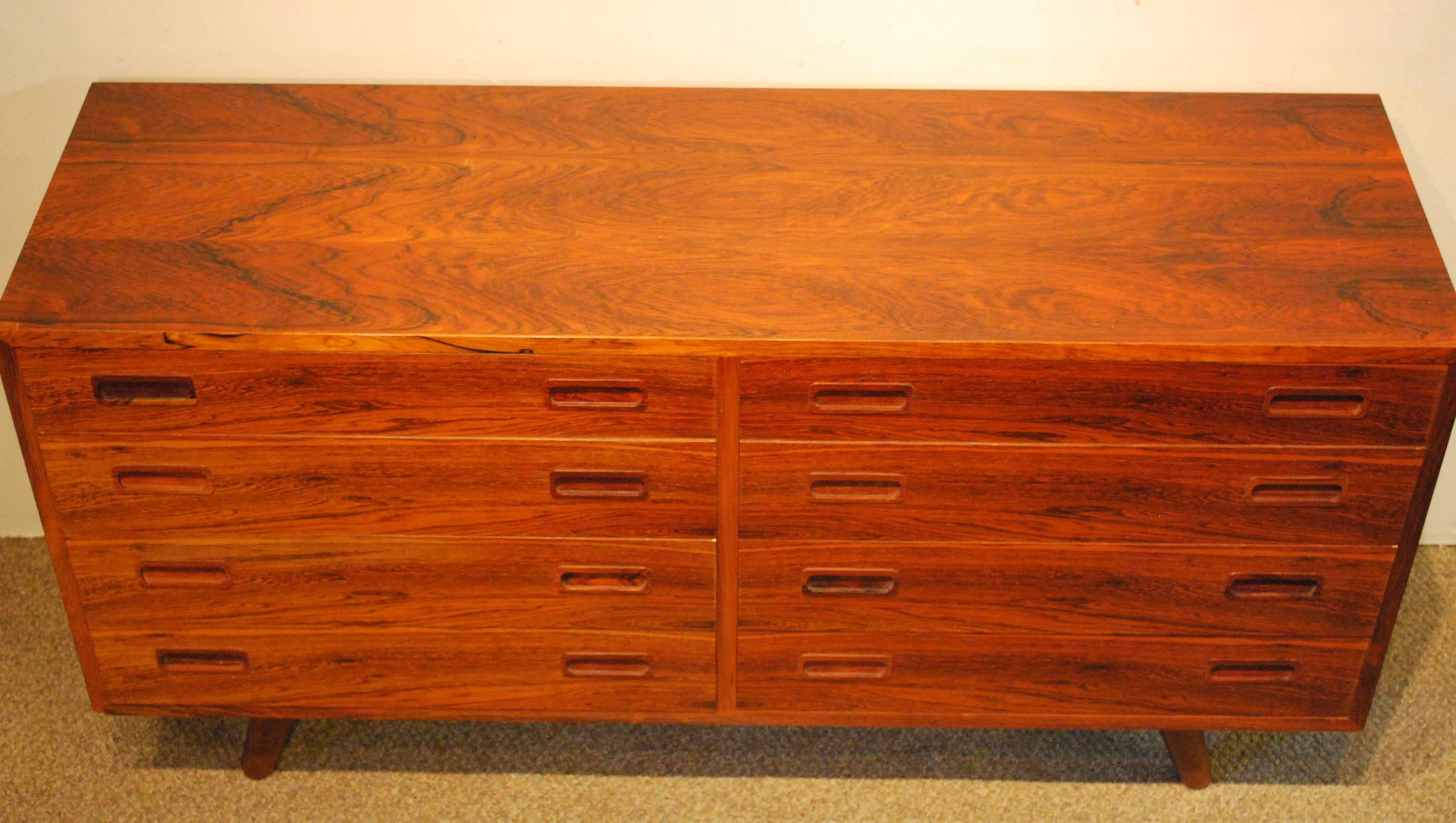 Large rosewood eight-drawer chest with continuous grain on all the rosewood surfaces. The hardwood interior is dovetailed on all joints. The factory mark and the Danish Mobelkontrol mark are visible on this piece. Note the Hansen like mitered