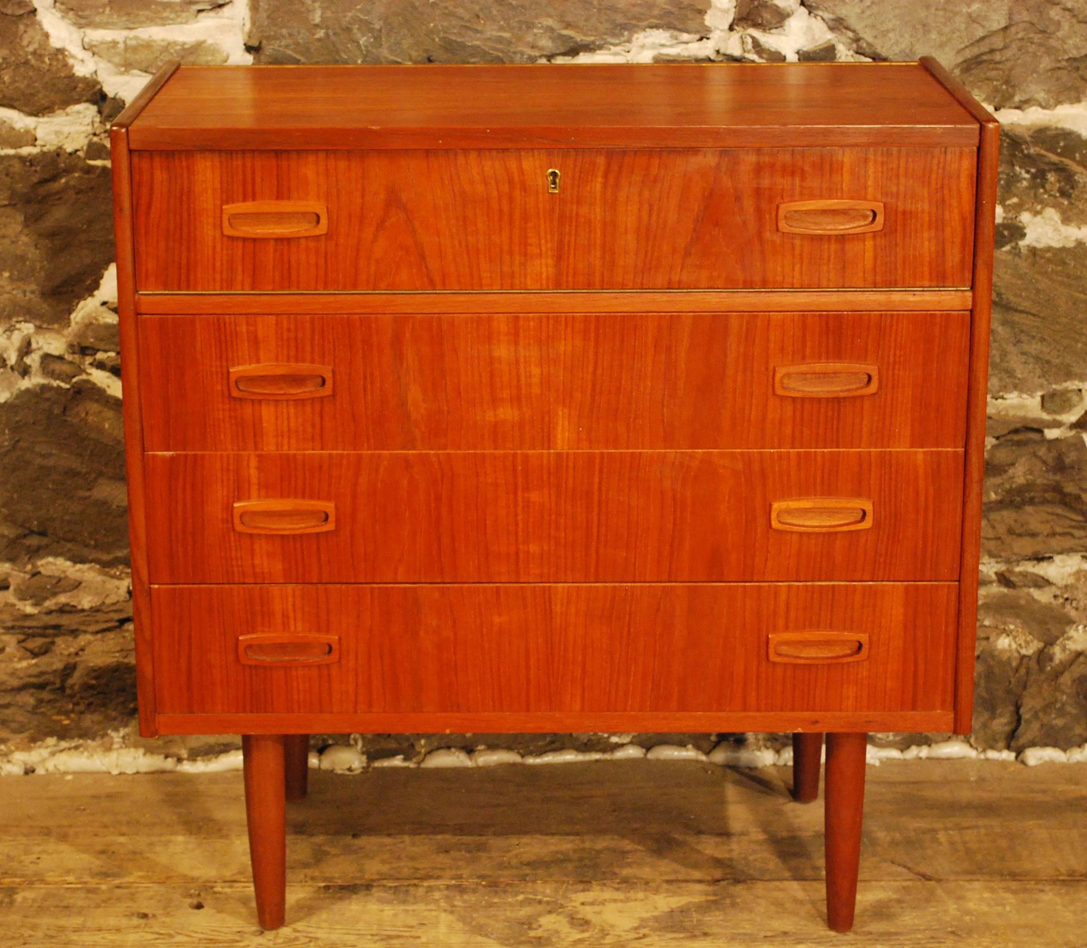 Mid-Century Modern teak small vanity/chest displaying a matched grain front with three dovetailed drawers with shaped pulls and a hinged top that opens to reveal interior storage and a mirror.