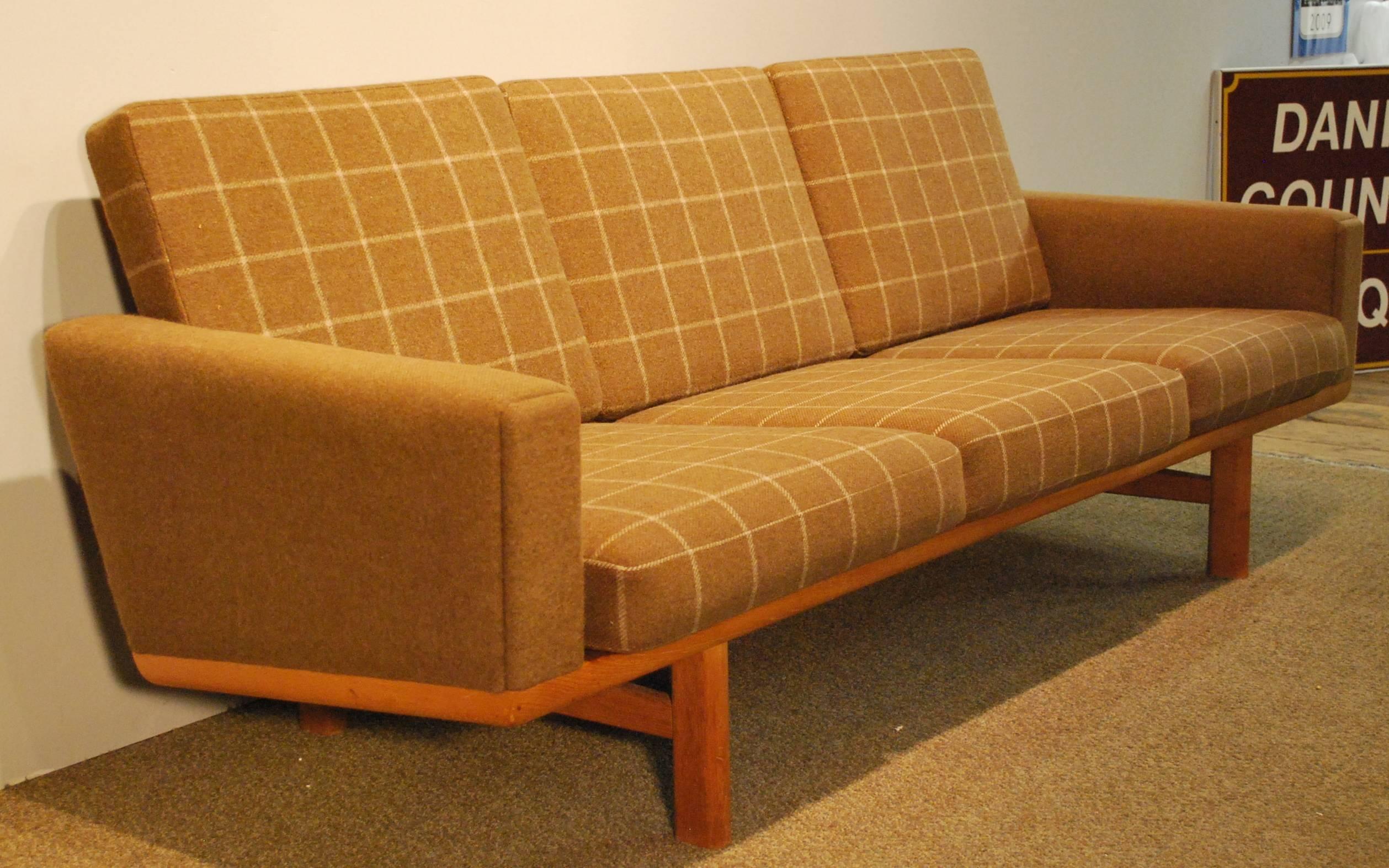 A Hans Wegner designed Mid-Century Modern sofa, Model 236, manufactured by GETAMA Mobelfabrik, and displaying a Classic wool blend fabric upholstered three cushion design in a simple beech wood slat back frame.