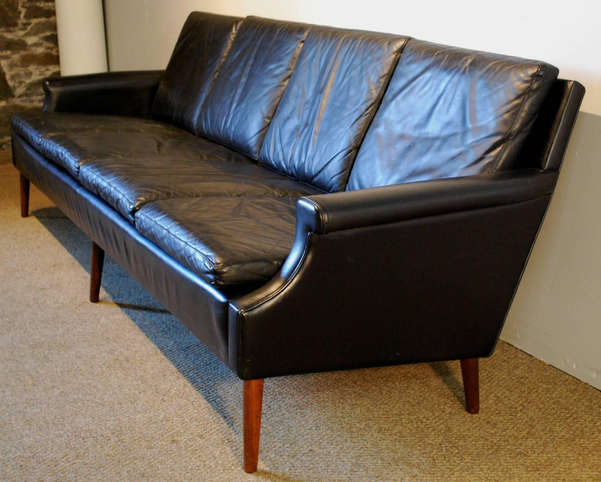 A Georg Thams designed Danish modern full grain black leather sofa featuring a Classic clean lined four cushion design. Elegant freestanding piece with no seams in the leather on the back which is quite unusual on a large sofa.