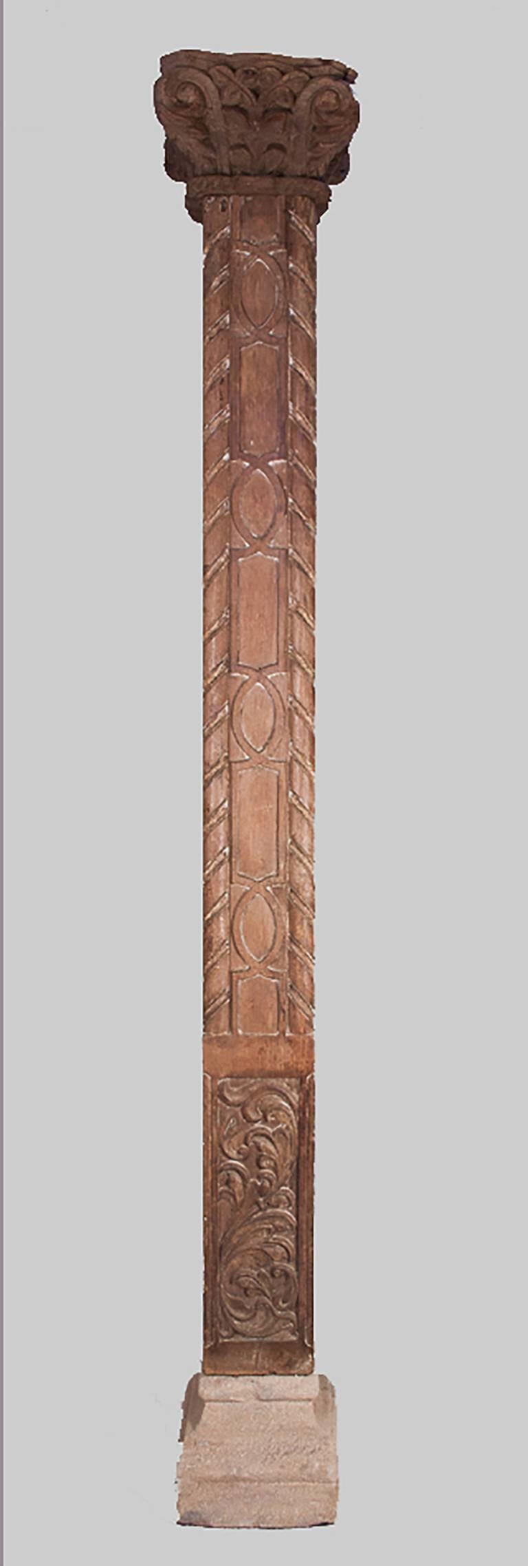 Pair of tall, slender, solid teak columns from Gujarat, India, circa 1880. These natural wood pillars feature very appealing hand-carved details accentuated by traces of original paint. Set in simple stone bases with relatively small footprints, the