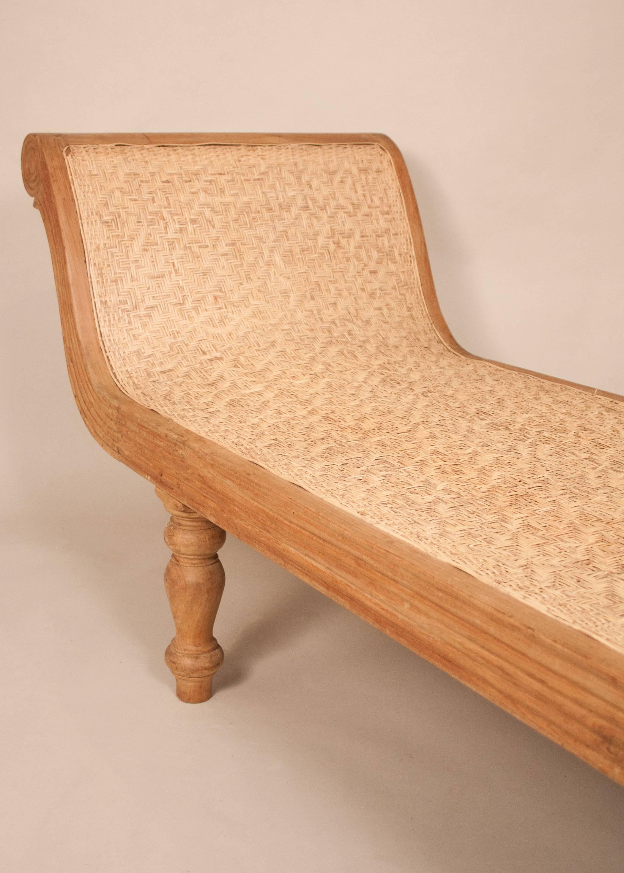 Long, sleek, tropical teak wood Anglo-Indian chaise lounges, circa 1970. This antique daybed features handwoven caning, simple carved details and shapely turned legs.
