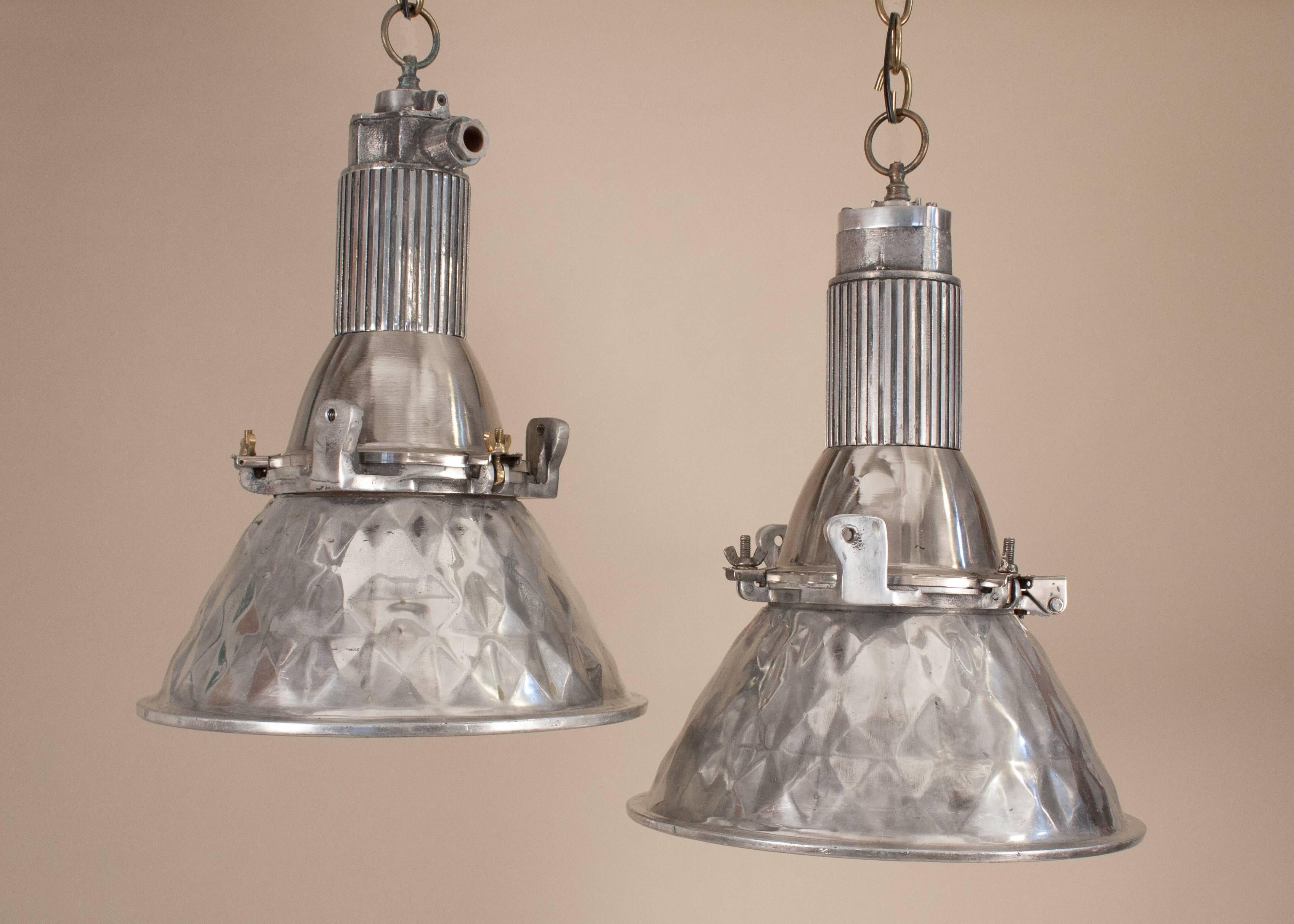 Pair of petite, polished aluminum Industrial pendant lights with pressed geometric pattern on the outside and inside of the shades. These small spotlights have been nicely restored and newly re-wired. Hinged enclosures help simplify bulb-changing.