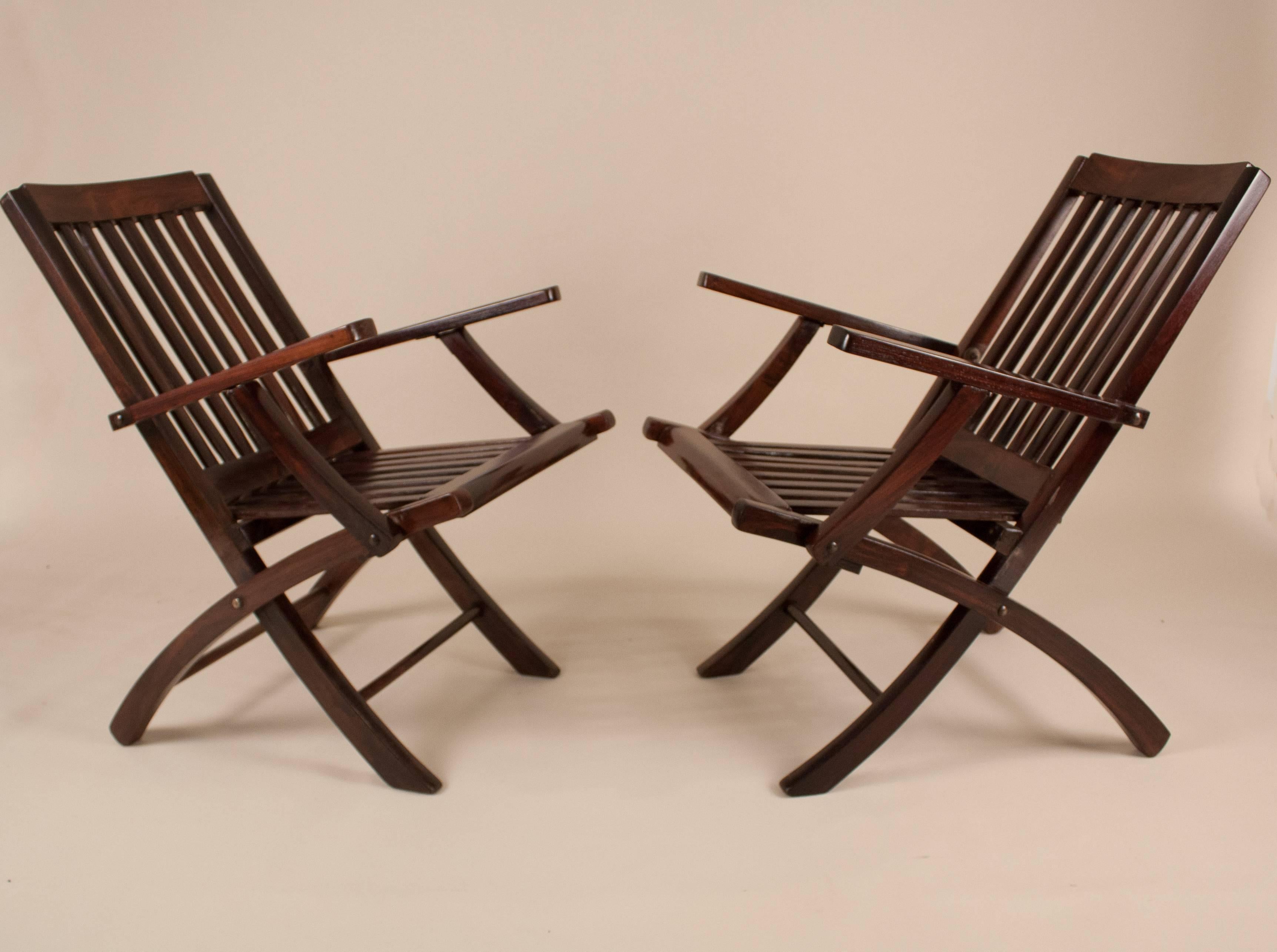 This pair of British folding steamer chairs evokes the romance of a 1940s voyage across the Indian Ocean. As stylish as they are practical, these portable deck chairs have beautiful lines and are crafted from richly refinished rosewood. The slatted