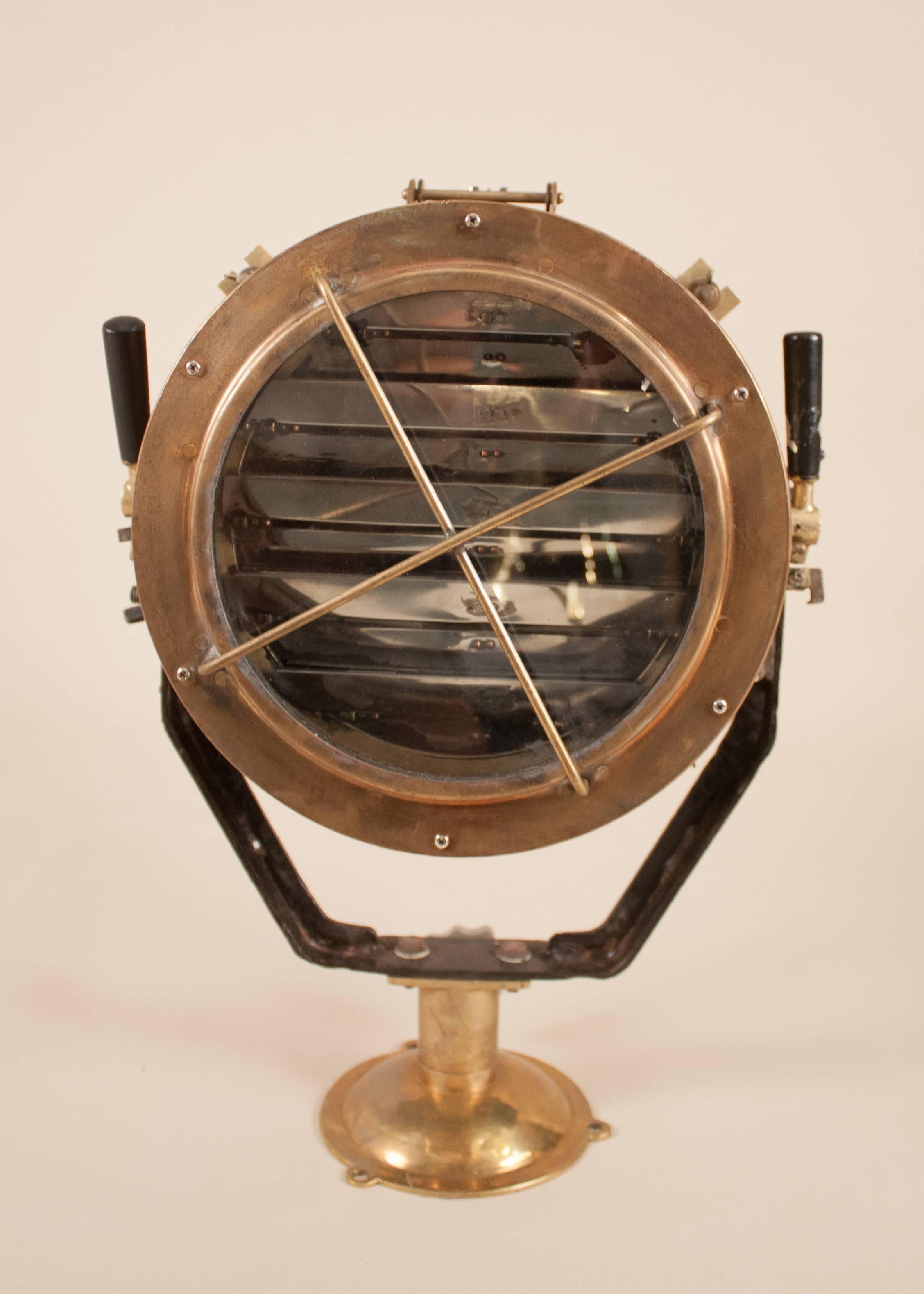 A solid brass daylight signaling lamp salvaged from a Japanese naval vessel and attentively restored. This mounted maritime spotlight features working aluminum signal shutters and sights, as well as multiple wooden levers/adjustments for