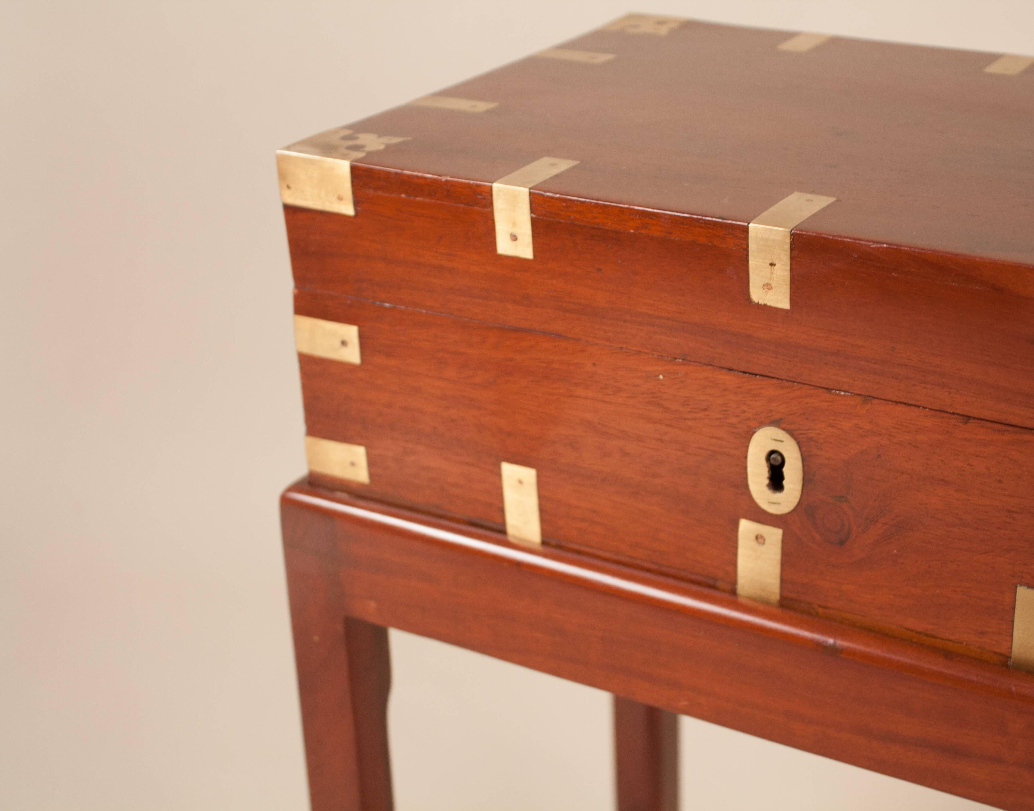 Late 19th century British Colonial fitted mahogany Campaign chest on a custom mahogany stand. This brass-bound officer's box features trays and compartments for personal effects, two inkwell receptacles and slatted storage on interior of lid for
