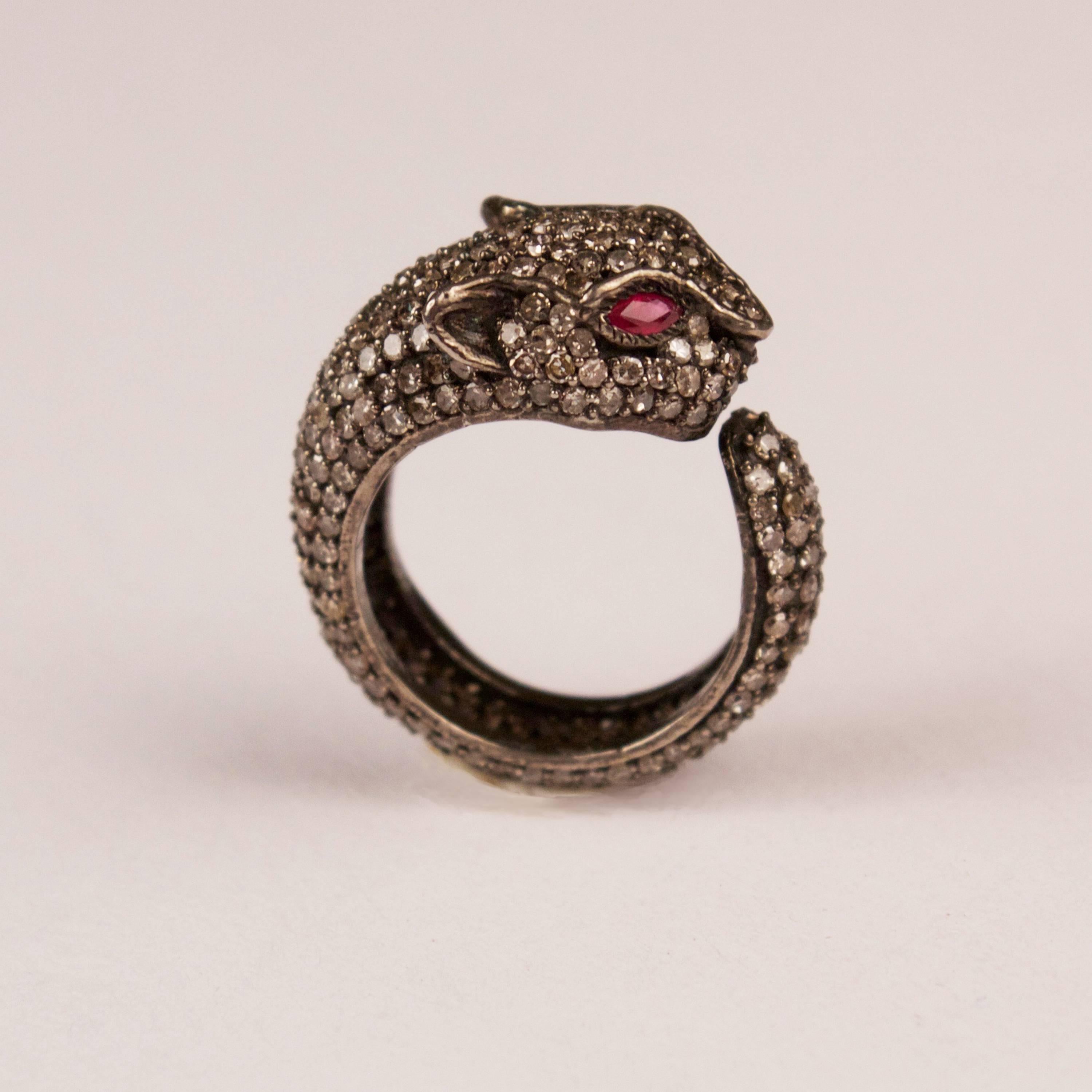 A panther ring with 3.50 carats of rose cut diamonds hand set in sterling silver. Featuring wonderful facial details, including red ruby eyes, this cougar transforms into a cuddly cat when head and tail wrap around the finger. Ring size is 7.