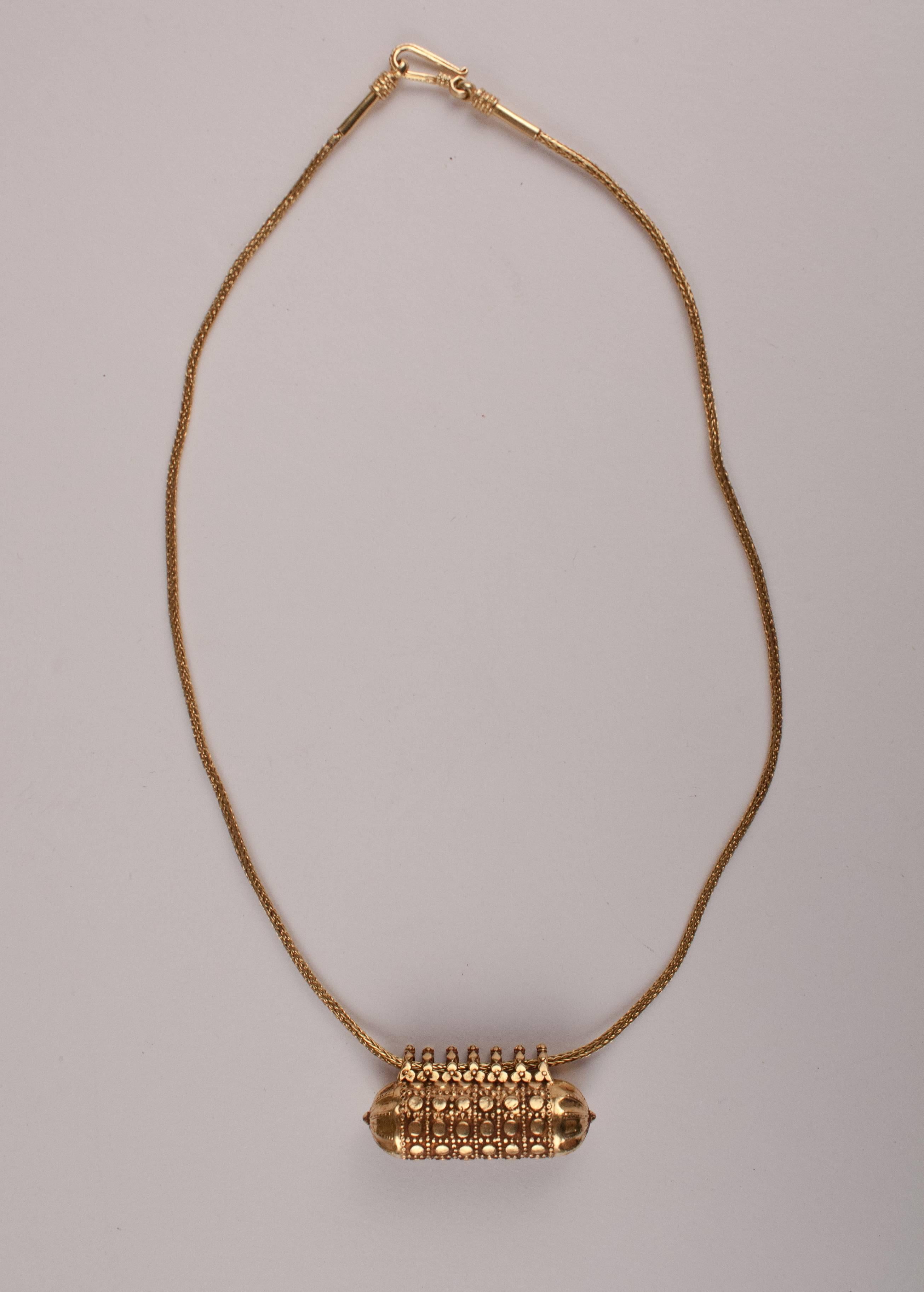 A special 18-karat gold amulet from India with a pleasing patina and tasteful granulation work, including floral details on each of the seven suspension loops. This capsule bead, which does not open, hangs from a contemporary 18-karat gold chain