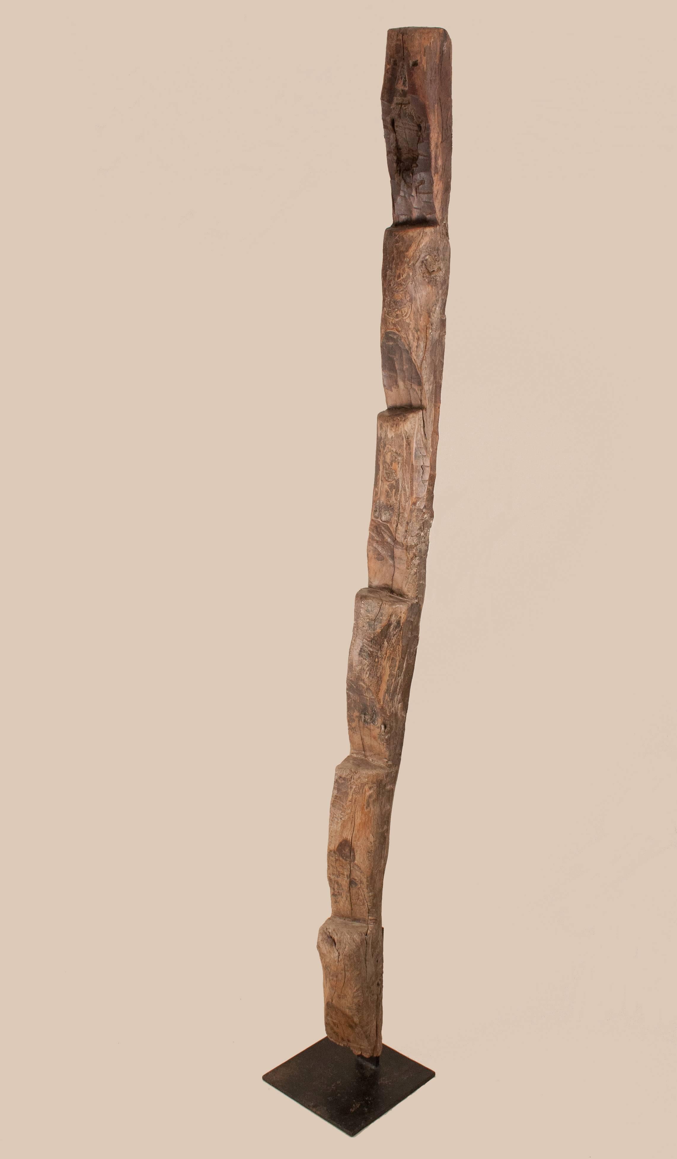 An exotic hardwood ladder from Nagaland in Northeast India. This seven-foot functional sculpture features a primitively carved face. The ladder is solidly mounted on a black iron base. Originally used to climb to raised dwellings, this hand-carved
