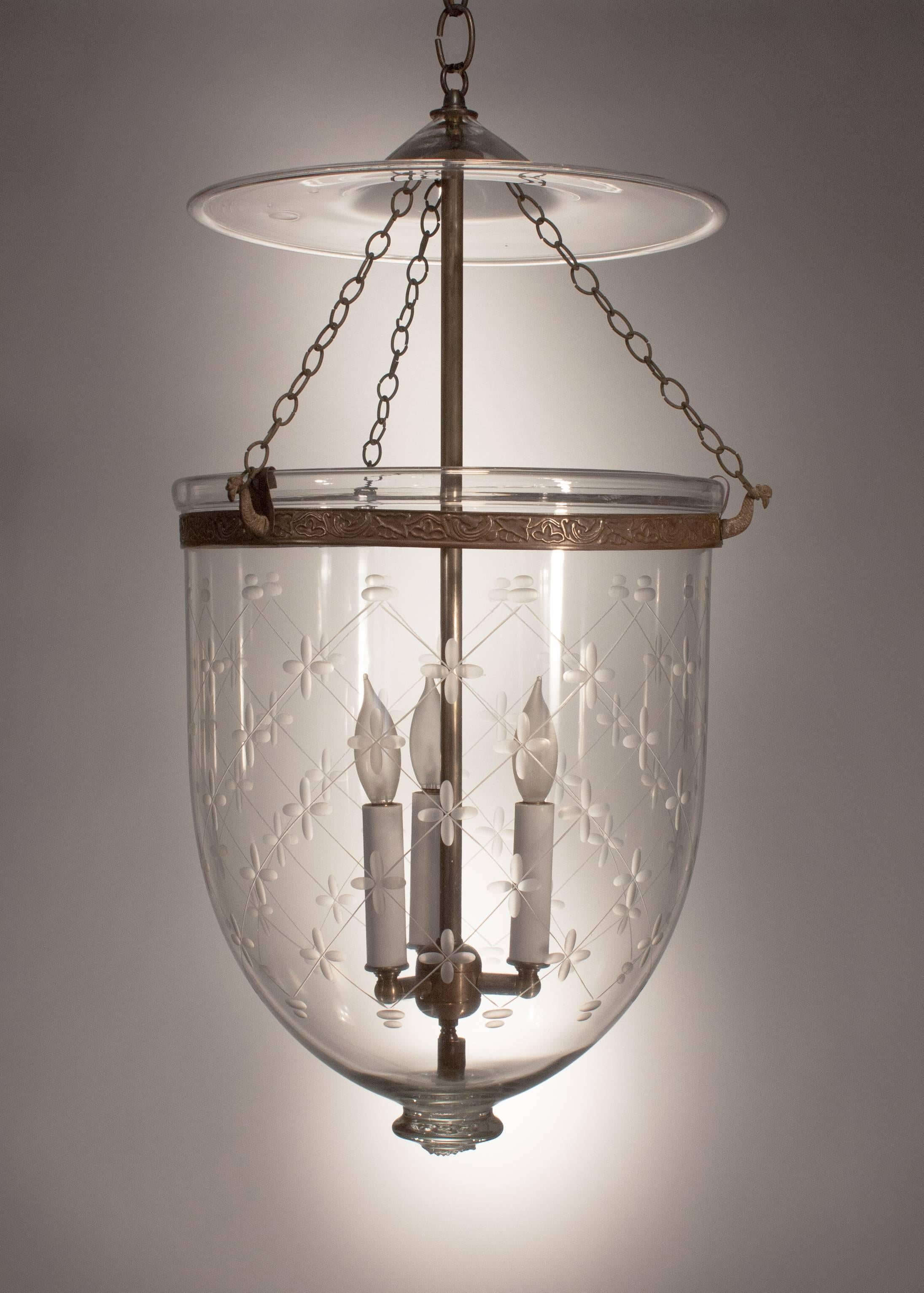 This exquisite English hall lantern features quintessential form and superb quality handblown glass, replete with desirable swirls and air bubbles. It has its original smoke bell and an embossed brass band with vine design. In addition, the finely