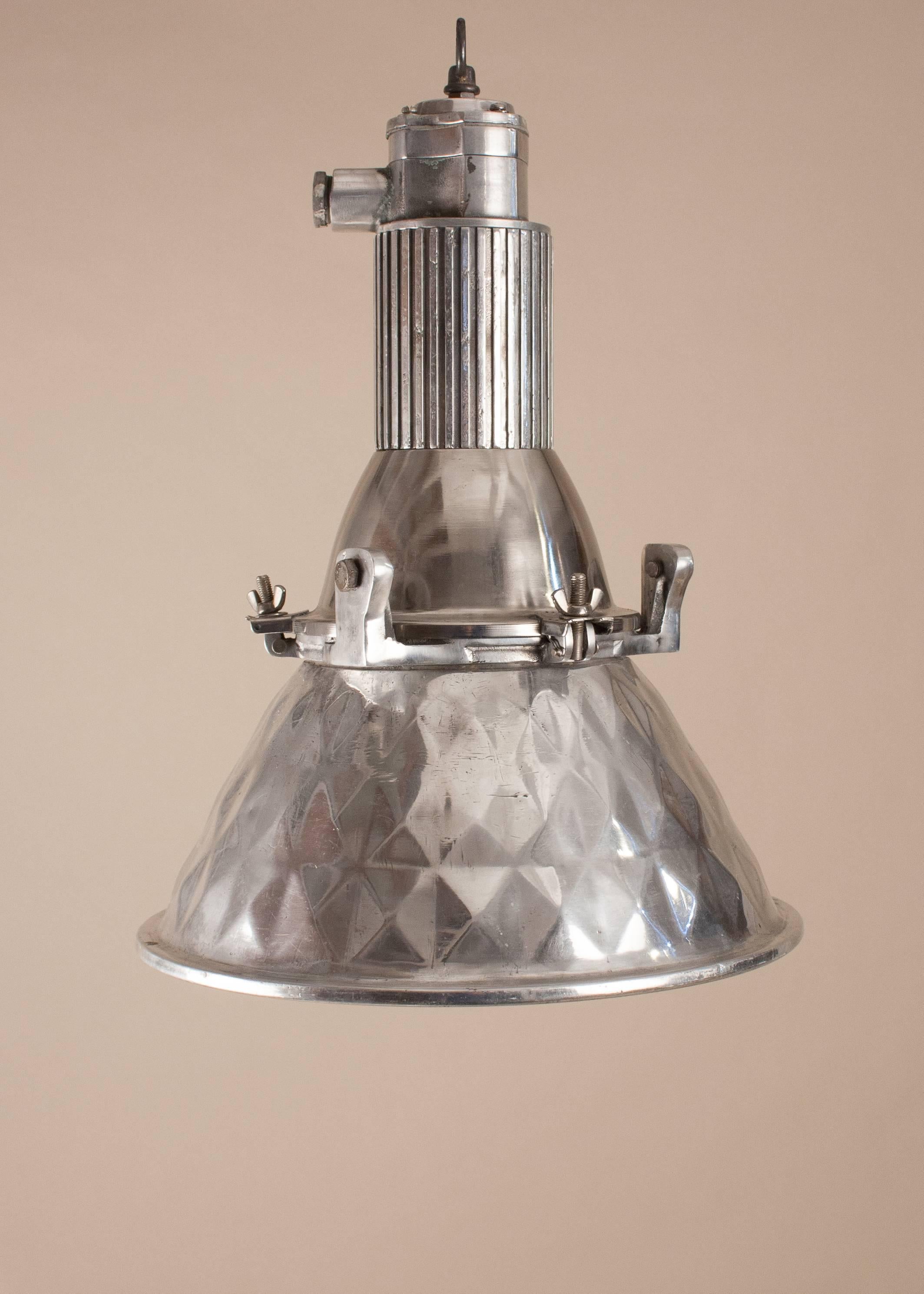 Mid-Century polished aluminum industrial or nautical spotlight with a pressed geometric pattern on both the outside and inside of the shade. The pendant's modest size makes it perfect in most any space. The light has been professionally restored and