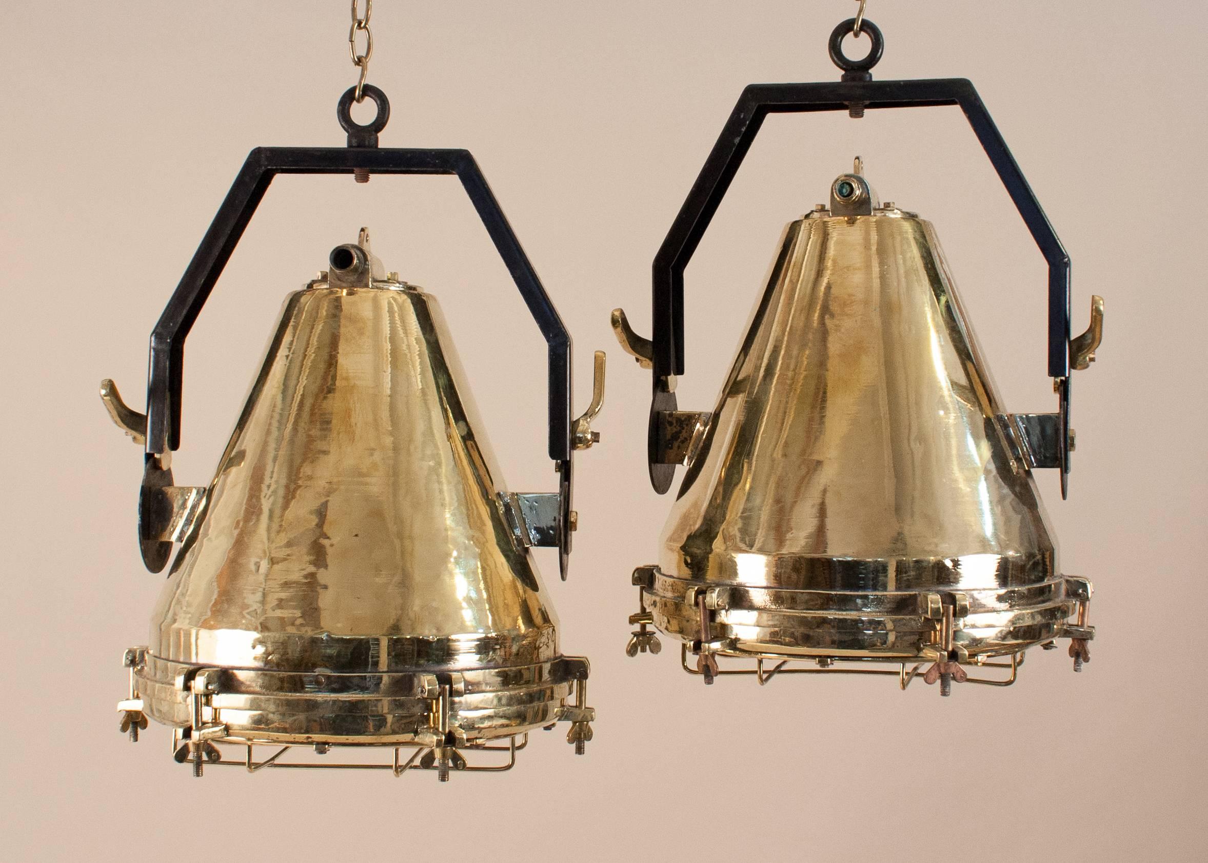 Rare and authentic pair of Mid-Century extra-large polished brass nautical spotlights with great form and patina. Salvaged from a maritime vessel and restored to near-original condition, these fabulous Industrial pendants suspend from adjustable