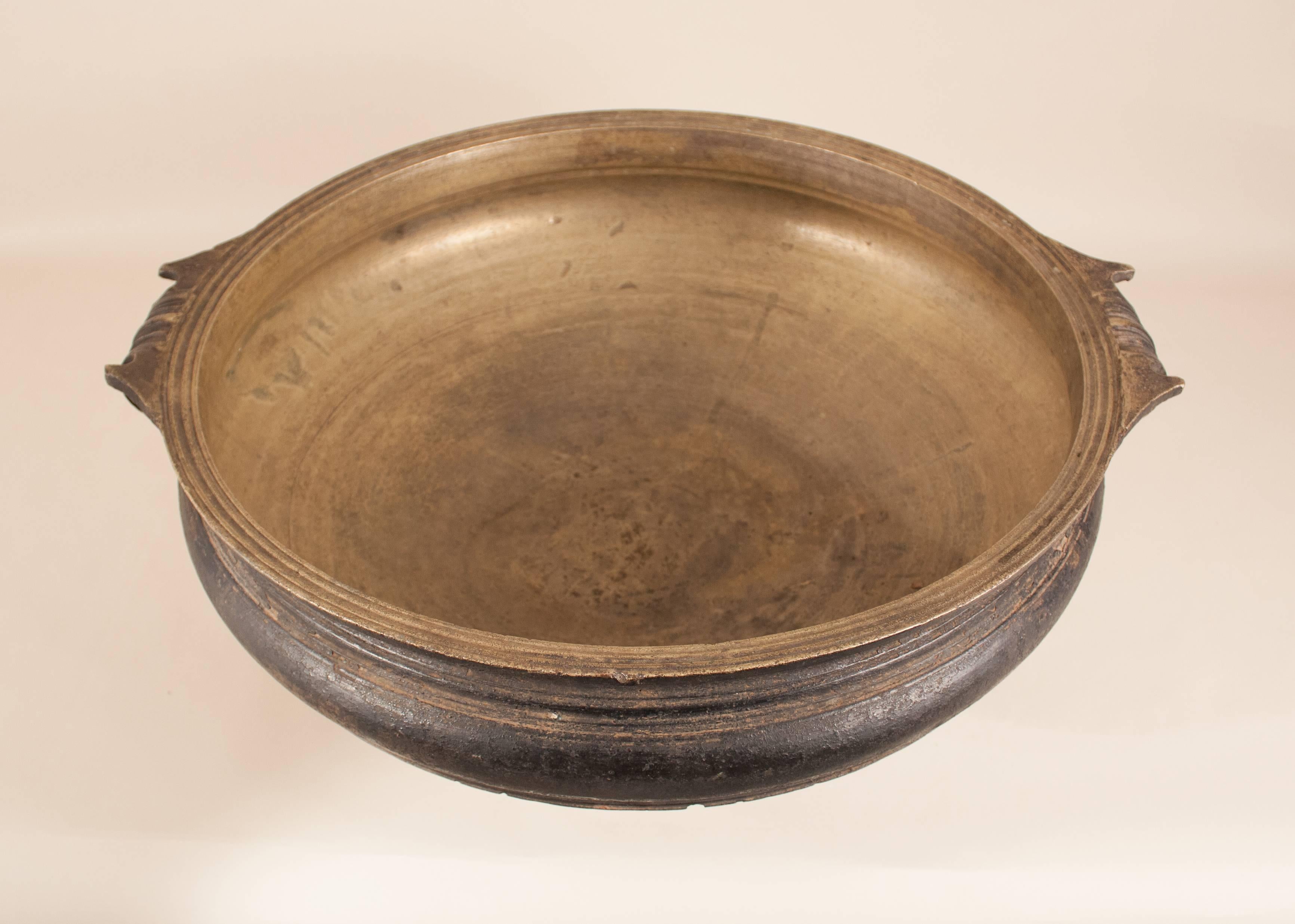 An antique solid bronze urli from Kerala, India, circa 1870. This authentic hand cast decorative vessel has wonderful patina and traditional form with scrolled handles. Still used for cooking at weddings and other celebrations in South East Asia,