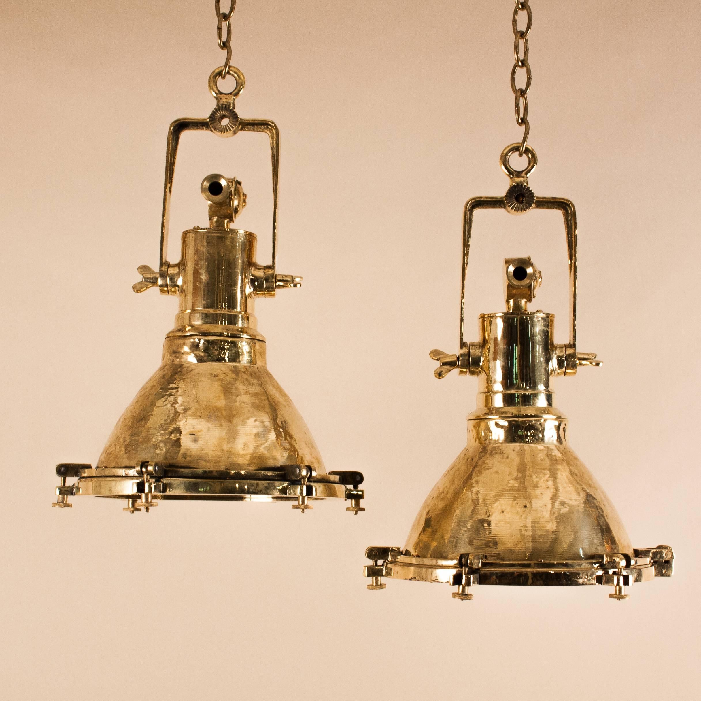 Superb pair of authentic, smaller scale nautical/Industrial pendants in polished brass with adjustable brass brackets, brass interiors and flat tempered glass lenses. These 1940s maritime lights have been attentively restored and newly rewired with