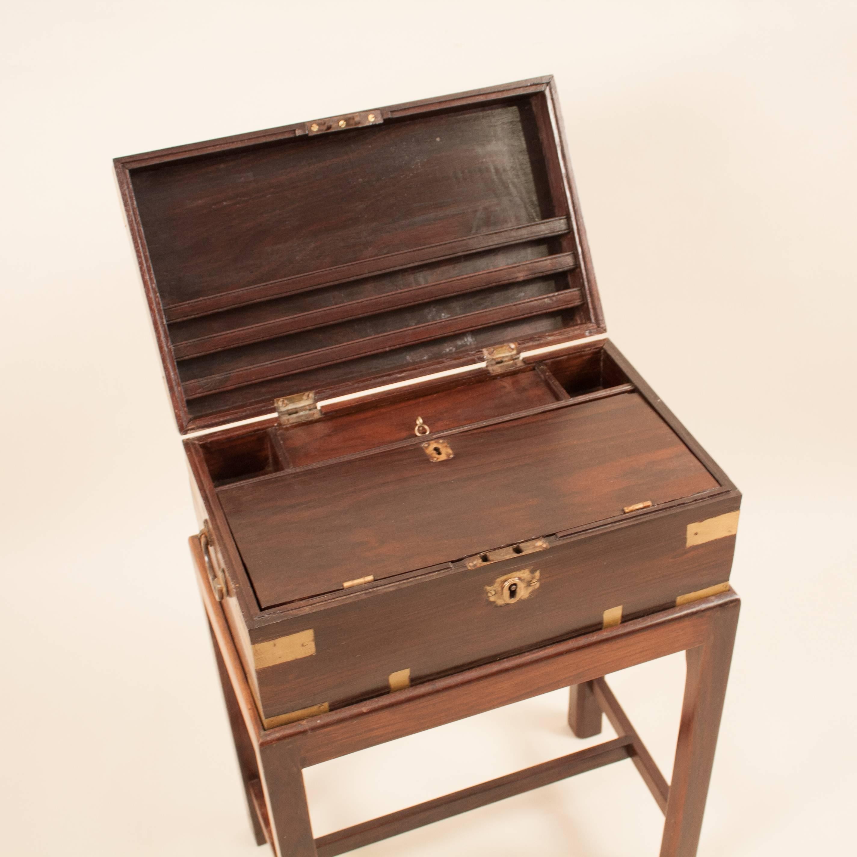 British Colonial fitted, brass-bound rosewood Campaign chest on a custom rosewood stand, circa 1900. This handsome officer's box has been attentively restored and features: exterior and interior working locks and keys; original carrying handles;