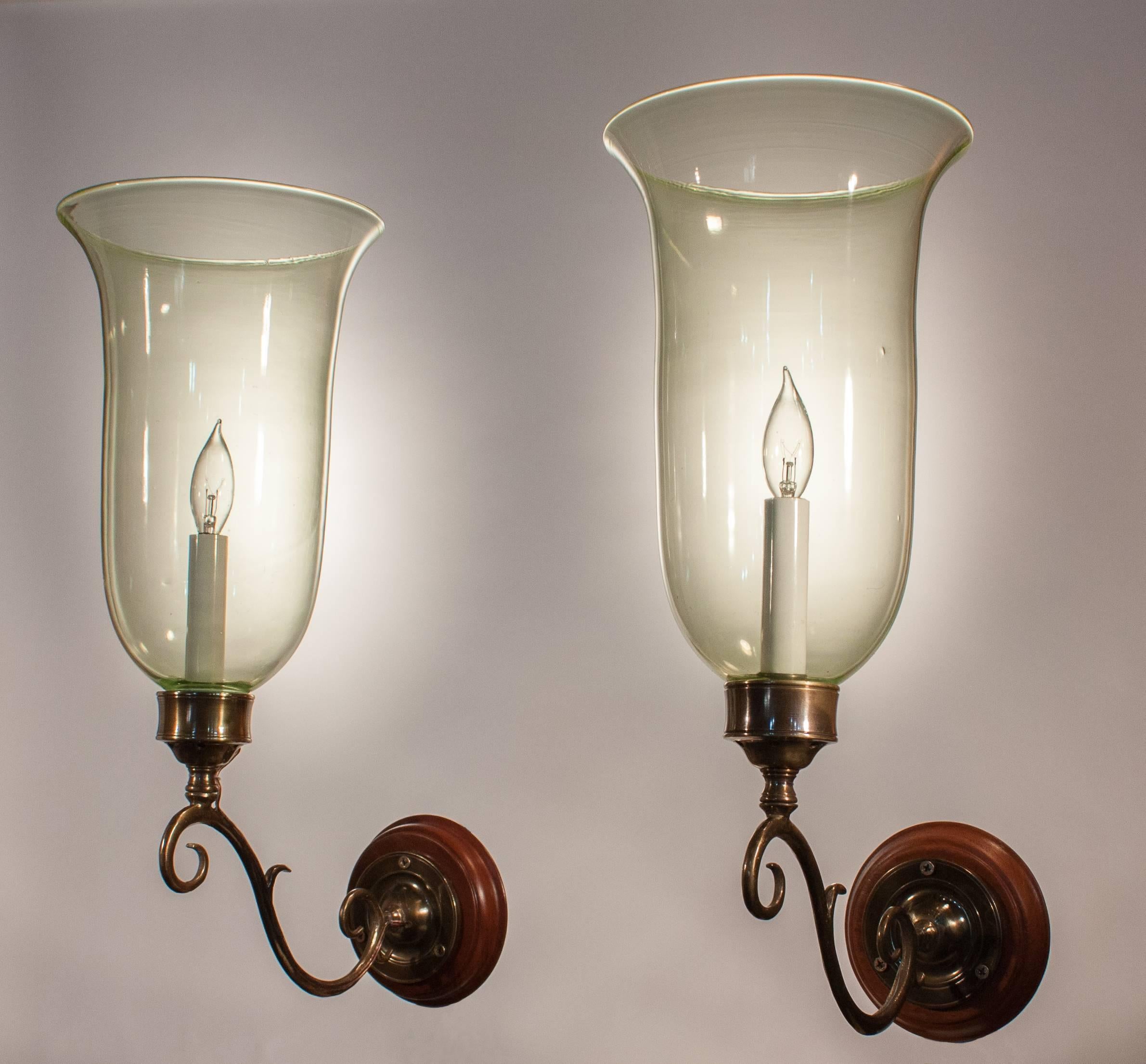 A rare and exceptional pair of late 19th century English hurricane shades with full flared form and subtly tinted vaseline-colored handblown glass. Originally for candles, the sconces have been newly electrified and cast a soft light from a single