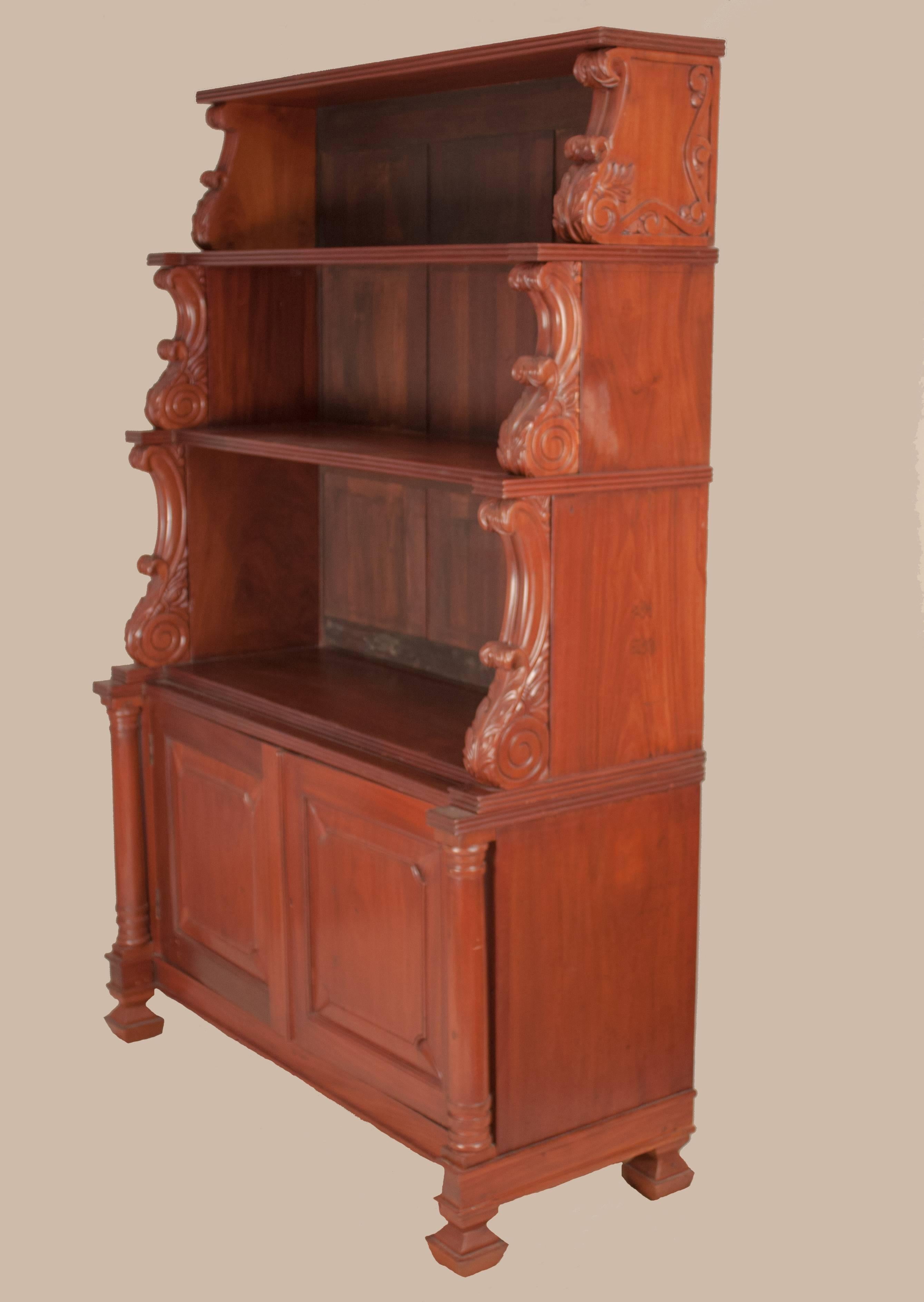 Indo-Portuguese hutch or display case in rich mahogany with carved acanthus details, circa 1900. The cabinet is in two parts with display shelves on top and a two-door cabinet with lock, bounded by columns, on the bottom. The back panels of the