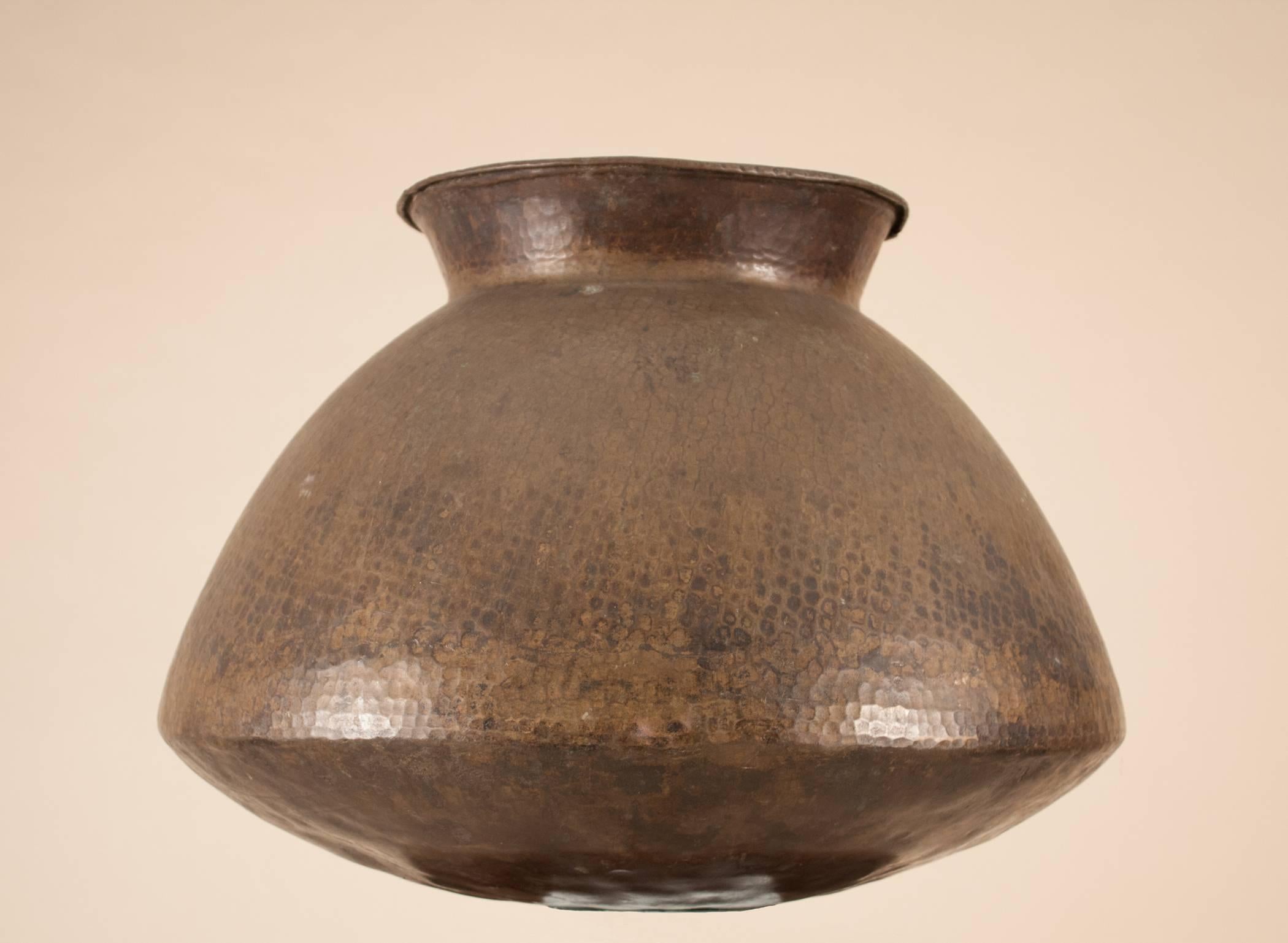 Originally used for water storage, this hand-hammered brass vessel from India has authentic texture, wonderful patina, and great form and character. The name name of the original owner is discretely inscribed on the side of the urn. The diameter at