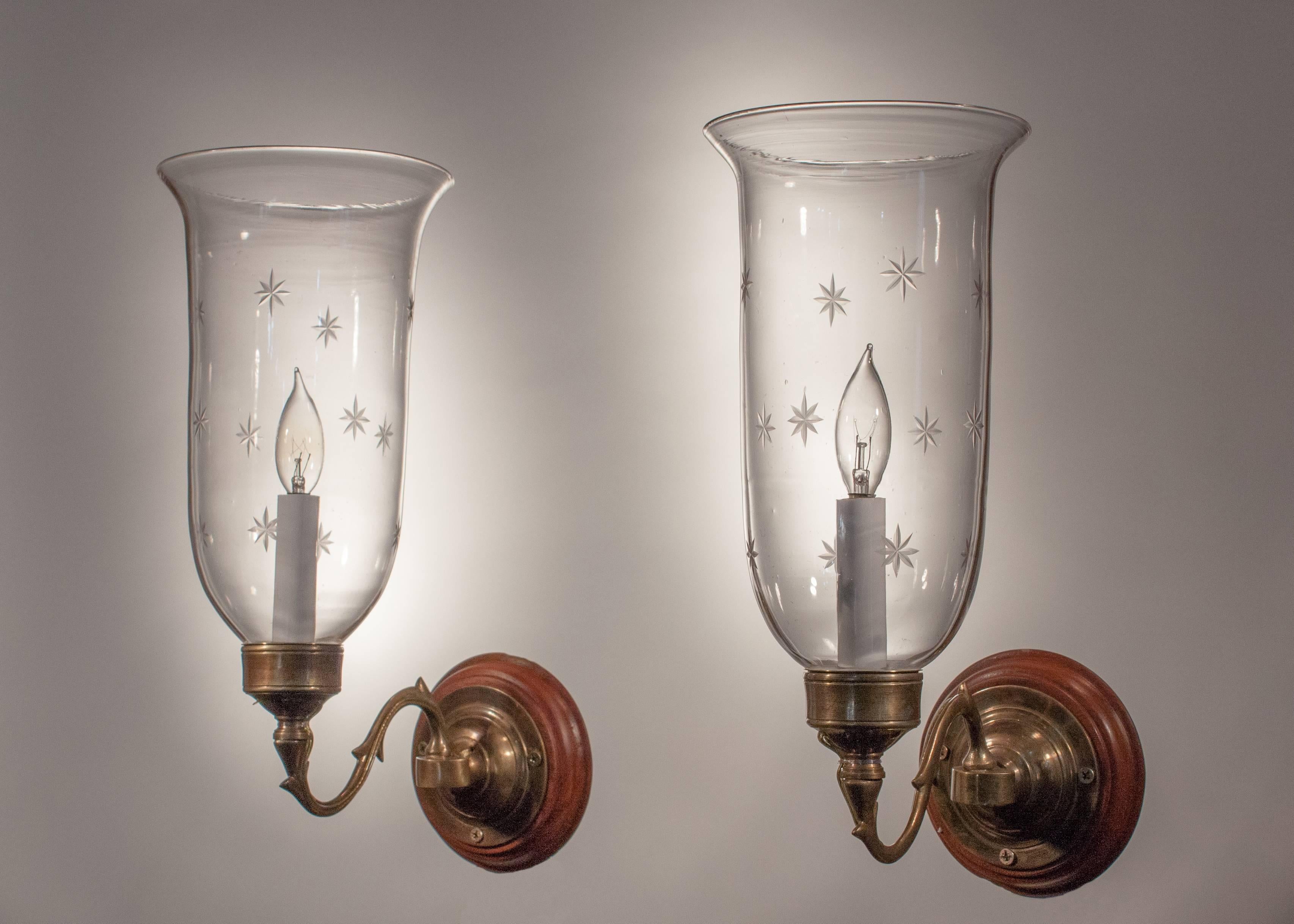 Lovely pair of 19th century English hand blown glass sconce shades with delicately flared form and fine star etching. These classic wall sconces are newly electrified, each using a single candelabra bulb up to 60 watts. Toned brass sconce arms and