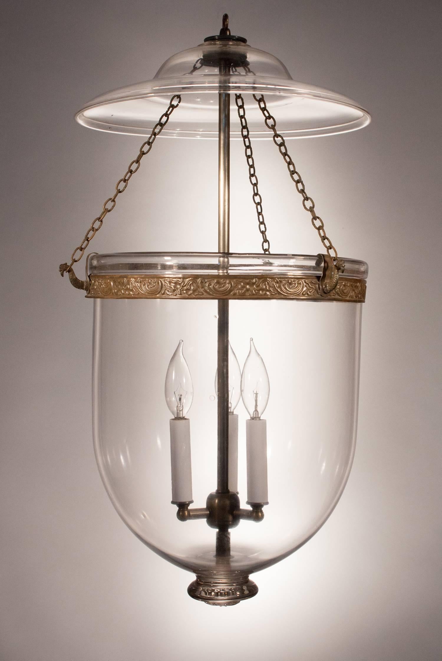 Generously sized and amply shaped, this antique English bell jar lantern features its original smoke bell and authentic brass band and chain. The pendant's proportions are superb, as is the clarity and quality of the hand blown glass. An especially
