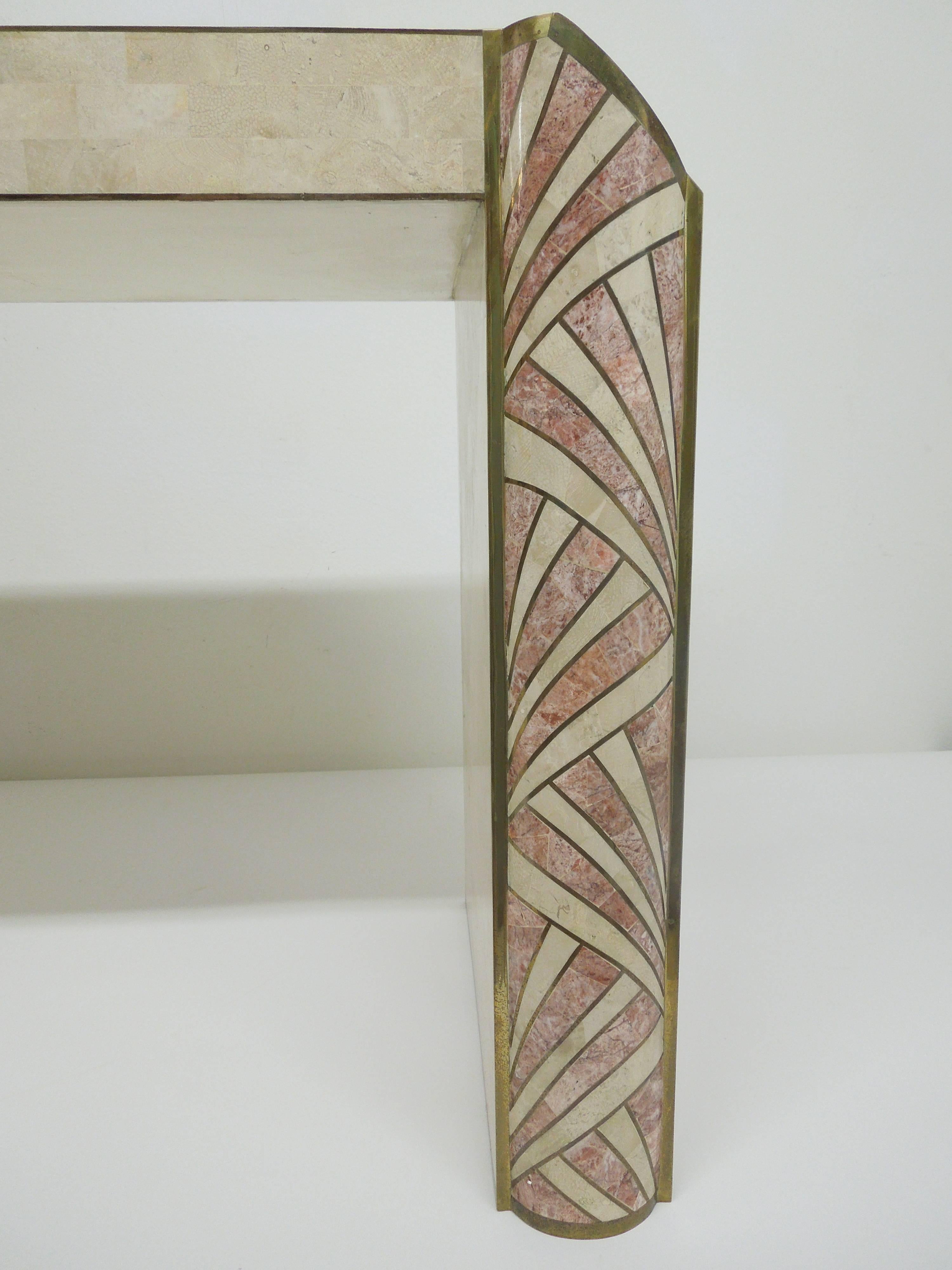 A handmade console table made of inlaid tessellated stone by Maitland-Smith. Brass trim. Ivory stone and rose color marble inlay. Signed on bottom with Maitland-Smith label.