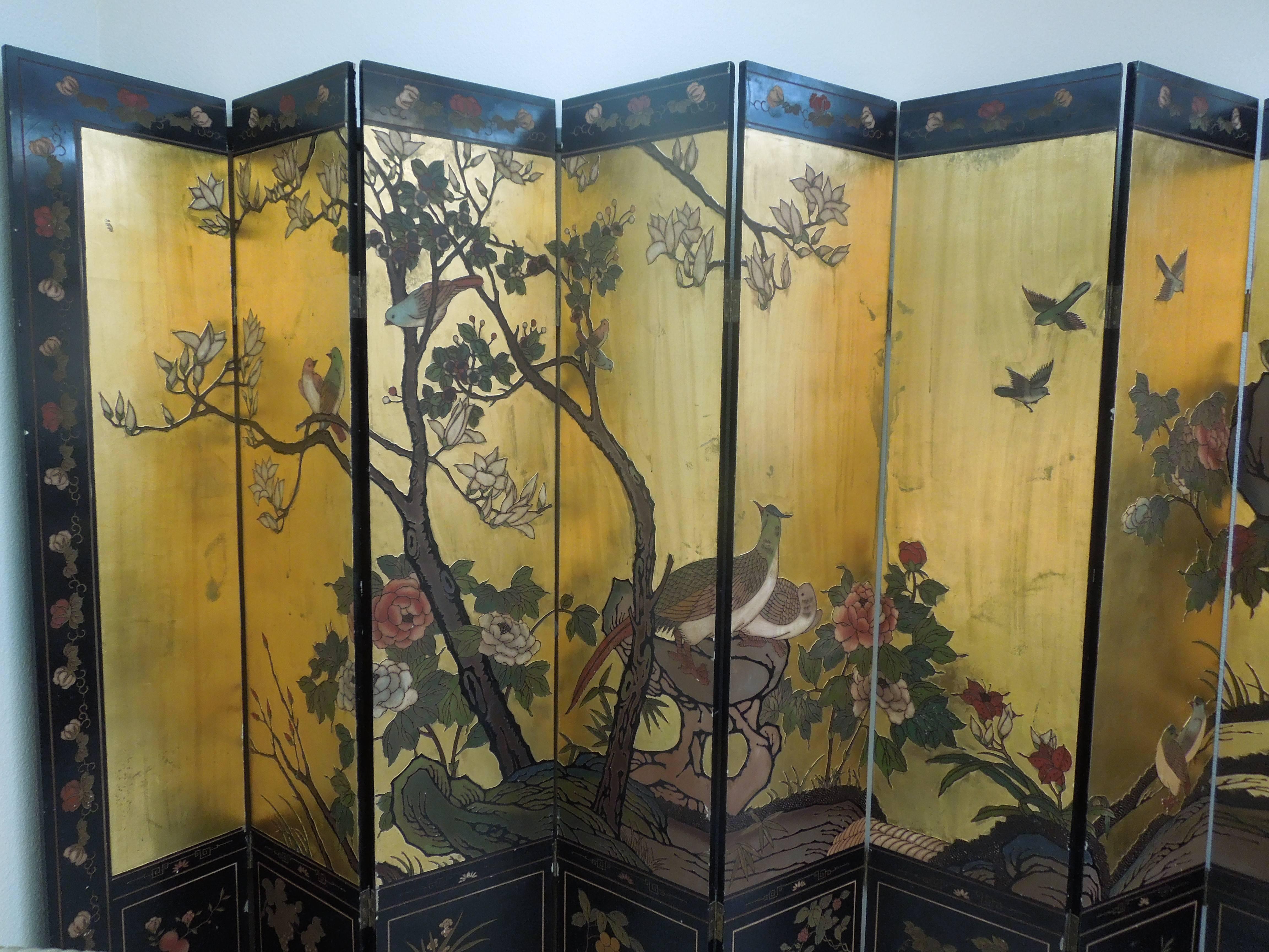 A unusual and very chic Chinese Coromandel eight-panel screen from the late 1940s. Beautiful carved detail in a very subtle, soothing floral and bird motif on antiqued color gold leaf. Framed on bottom with black squares that have a simple florals.