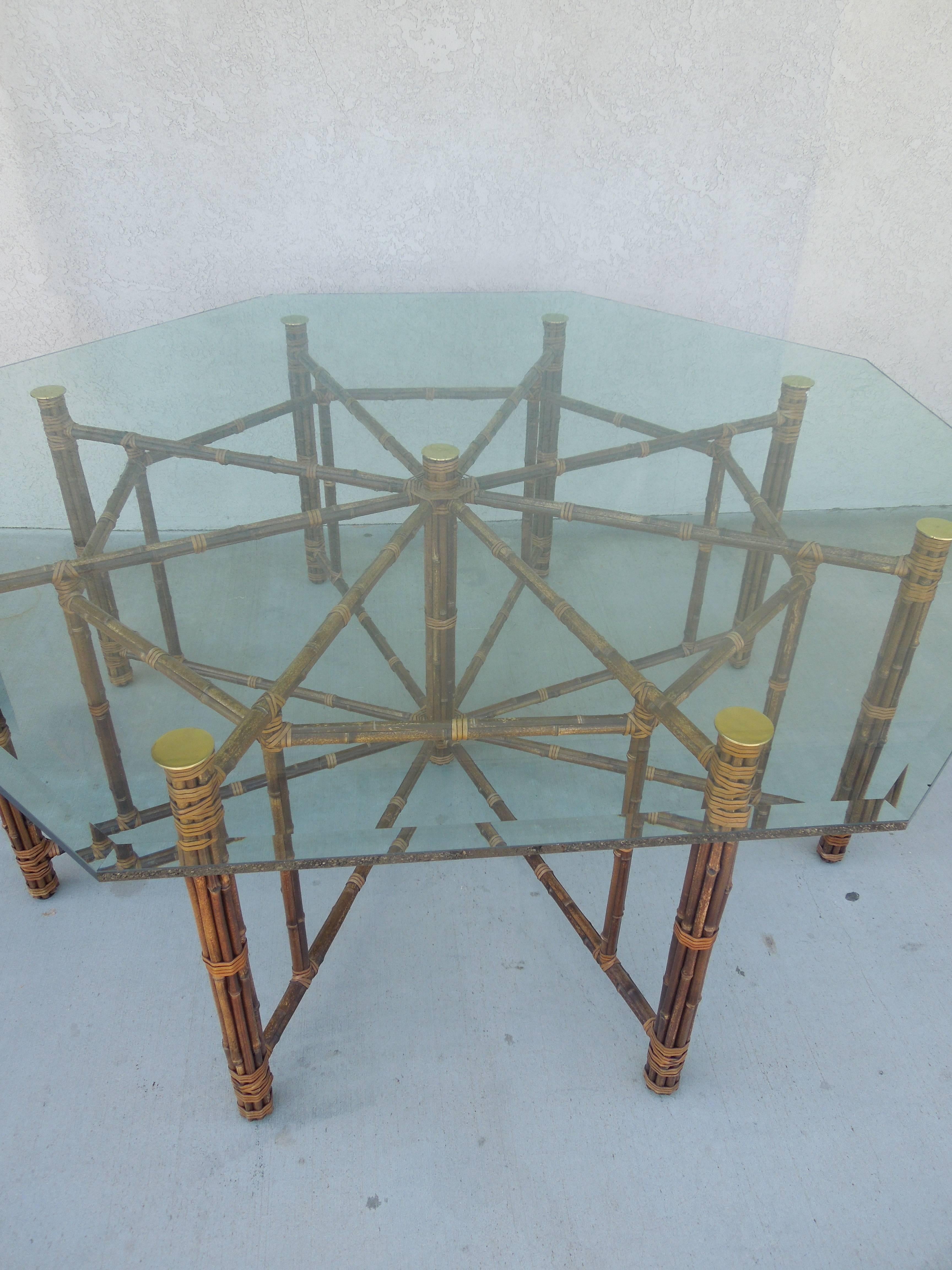 This large hexagonal dining table, designed by John McGuire, features bamboo poles lashed in place with McGuire's signature rawhide laces. A glass top reveals a center support of bundled bamboo. Horizontal bamboo members radiate from this center
