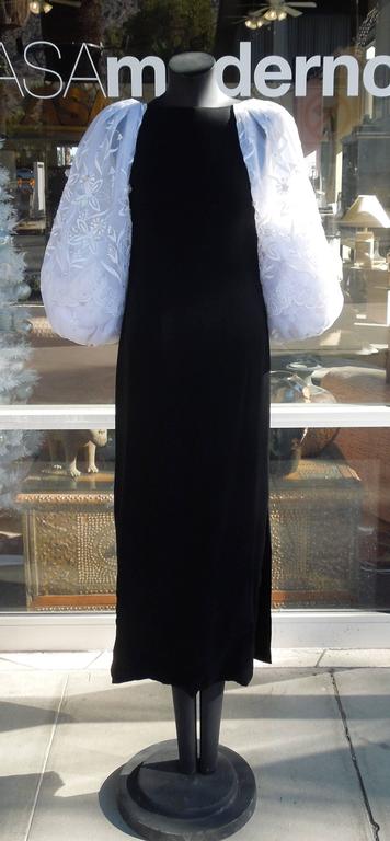 A very chic circa 1980s long black crepe evening dress with dramatic sheer white organza balloon sleeves, the sleeves are beautifully embroidered white on white and accented with rhinestones. Double slit hem. No size ticket. Measures: Shoulder