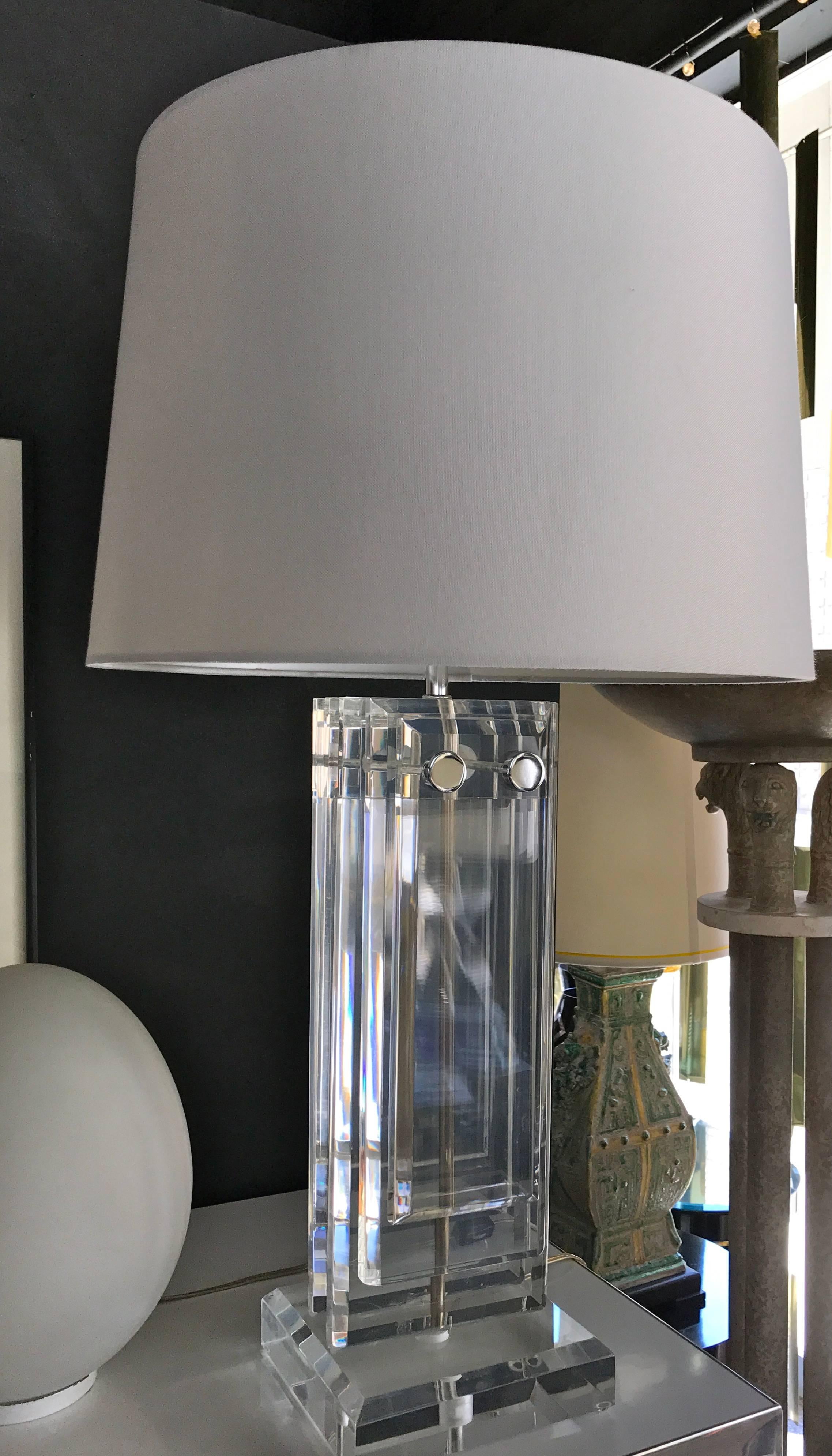 In the style of Pierre Cardin, a really special Lucite lamp from the 1970s. New white barrel shade. This lamp is heavy and made of thick solid slabs of Lucite. Lucite finial included. Chrome accent trim. From a very upscale and architecturally