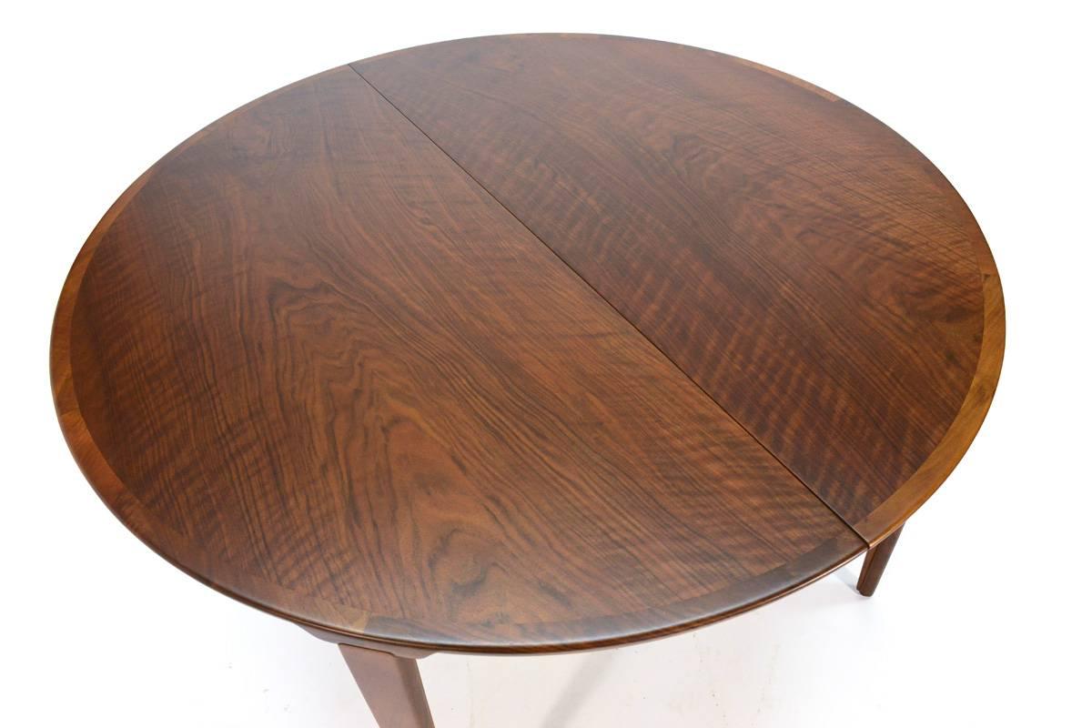 Fantastic round walnut dining table designed by Rosengren Hansen for Brandie Møbelfabrik. A very versatile piece with two leaves, one that folds in half and stores inside the table, allowing you to go from four to eight person seating easily. The
