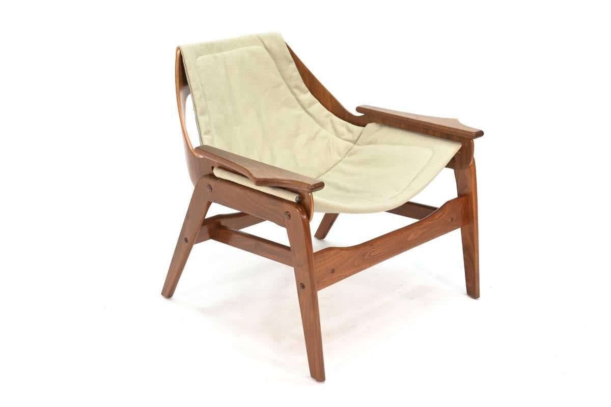 A walnut sling lounge chair designed by Jerry Johnson and produced by Plycraft. Really great sculptural shape. The frame appears to have been previously refinished, it shows very light normal wear from age and use. The sling is new. Seat height is