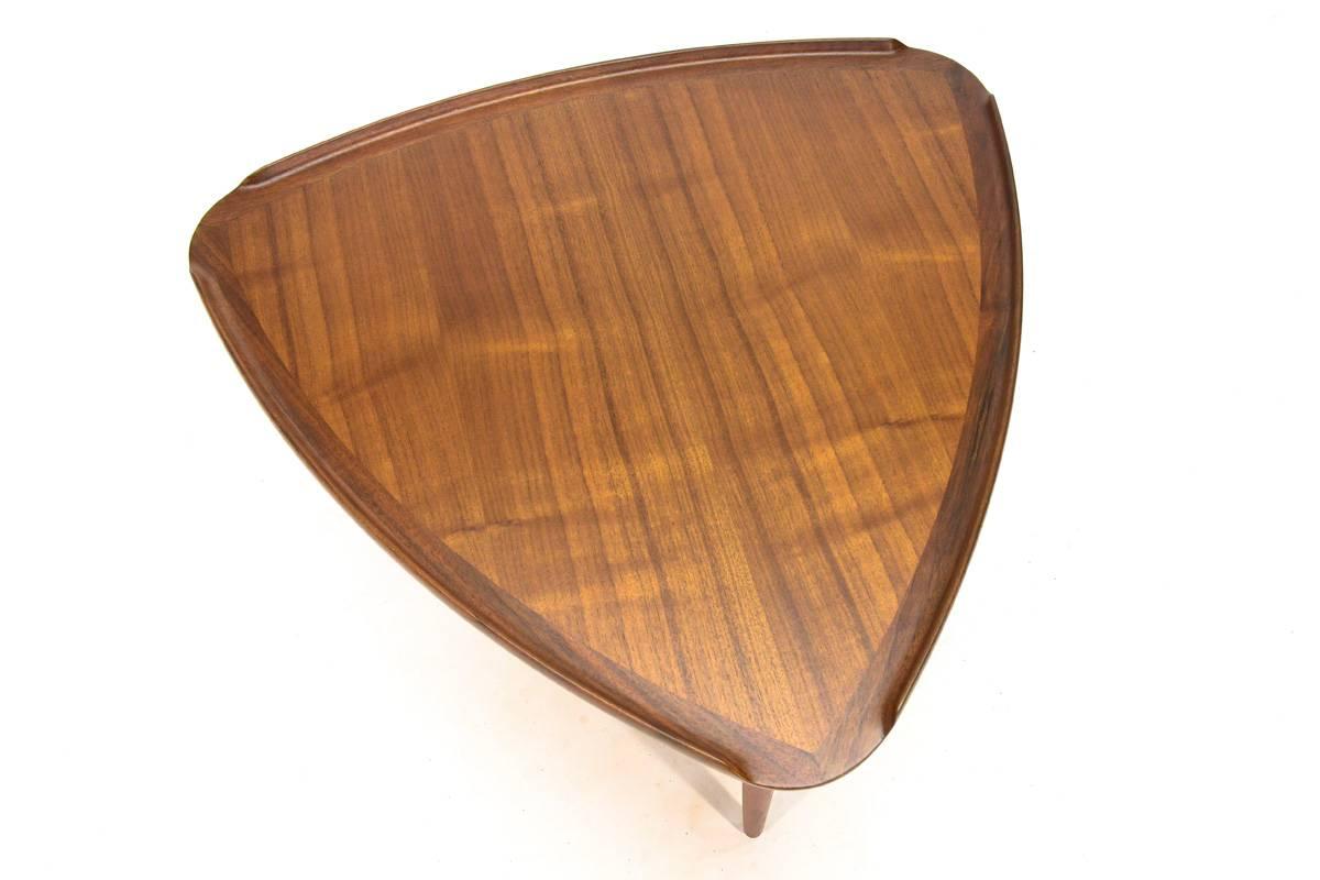 A Classic Danish side table designed by Poul Jensen for Selig. This example is done in teak. A great piece between a pair of lounge chairs. The beautifully caned lower shelf is in excellent original condition; the rest of the piece of the piece has