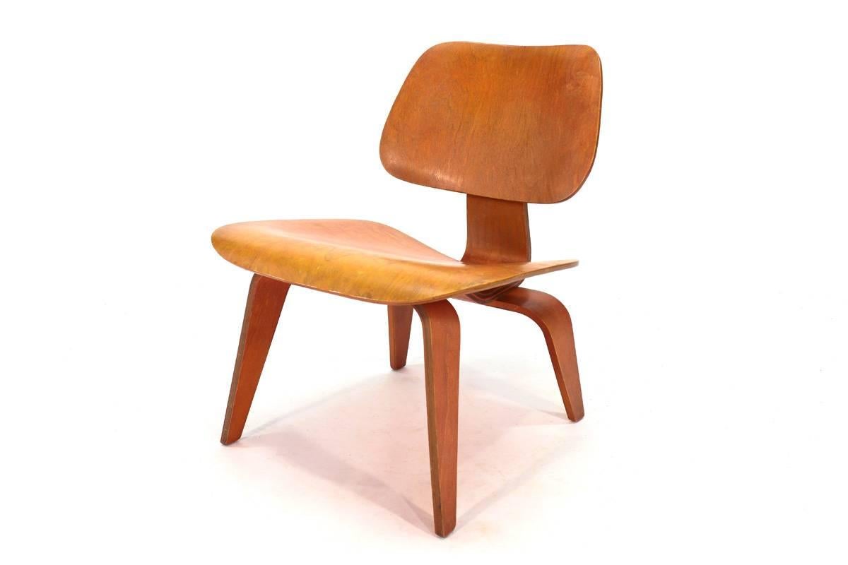 Very nice early Eames LCW in red. This piece is 100% original and shows a beautiful faded tone that makes the piece almost orange. The seat and legs show some light scratching and wear but there are no veneer chips or other significant damage. Seat