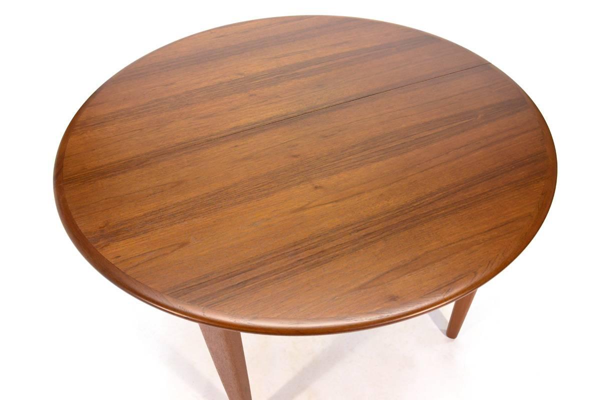 Absolutely stunning round teak dining table designed by Henning Kjaernulf for Soro Stole in 1962. This table extends from a petite 45