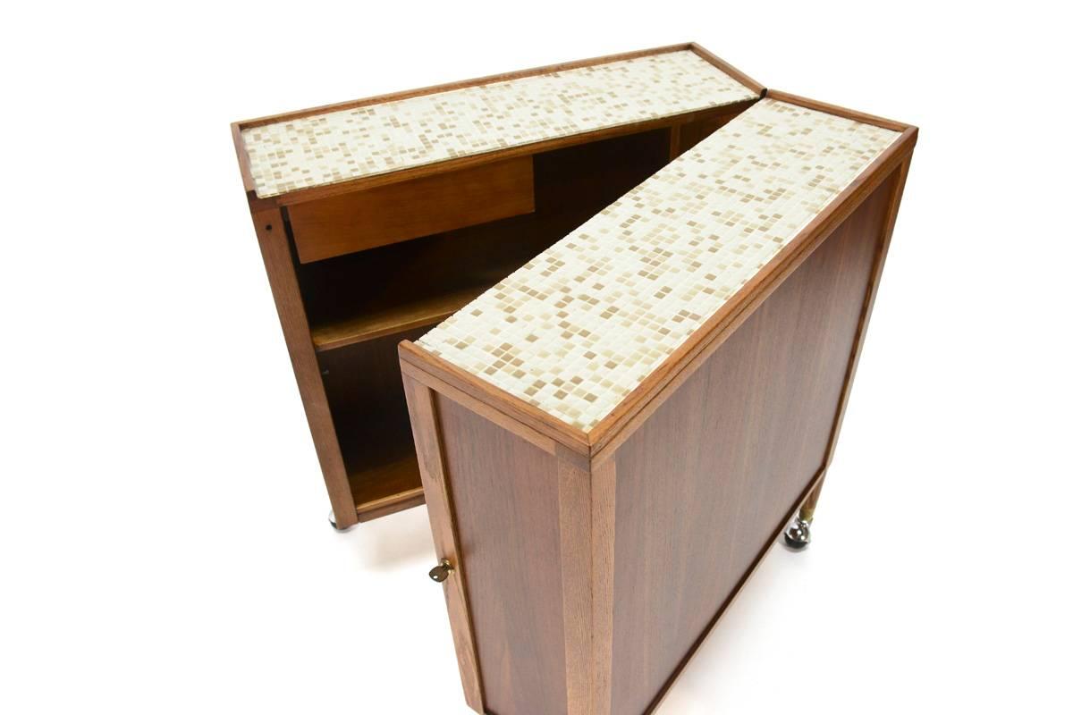 Very unique piece. Designed by Henry P. Glass and produced by Saginaw Furniture. What starts an unassuming walnut cabinet on wheels unlocks and opens up to almost 90 degrees (just a bit less so it doesn’t tip over) revealing ample storage for a
