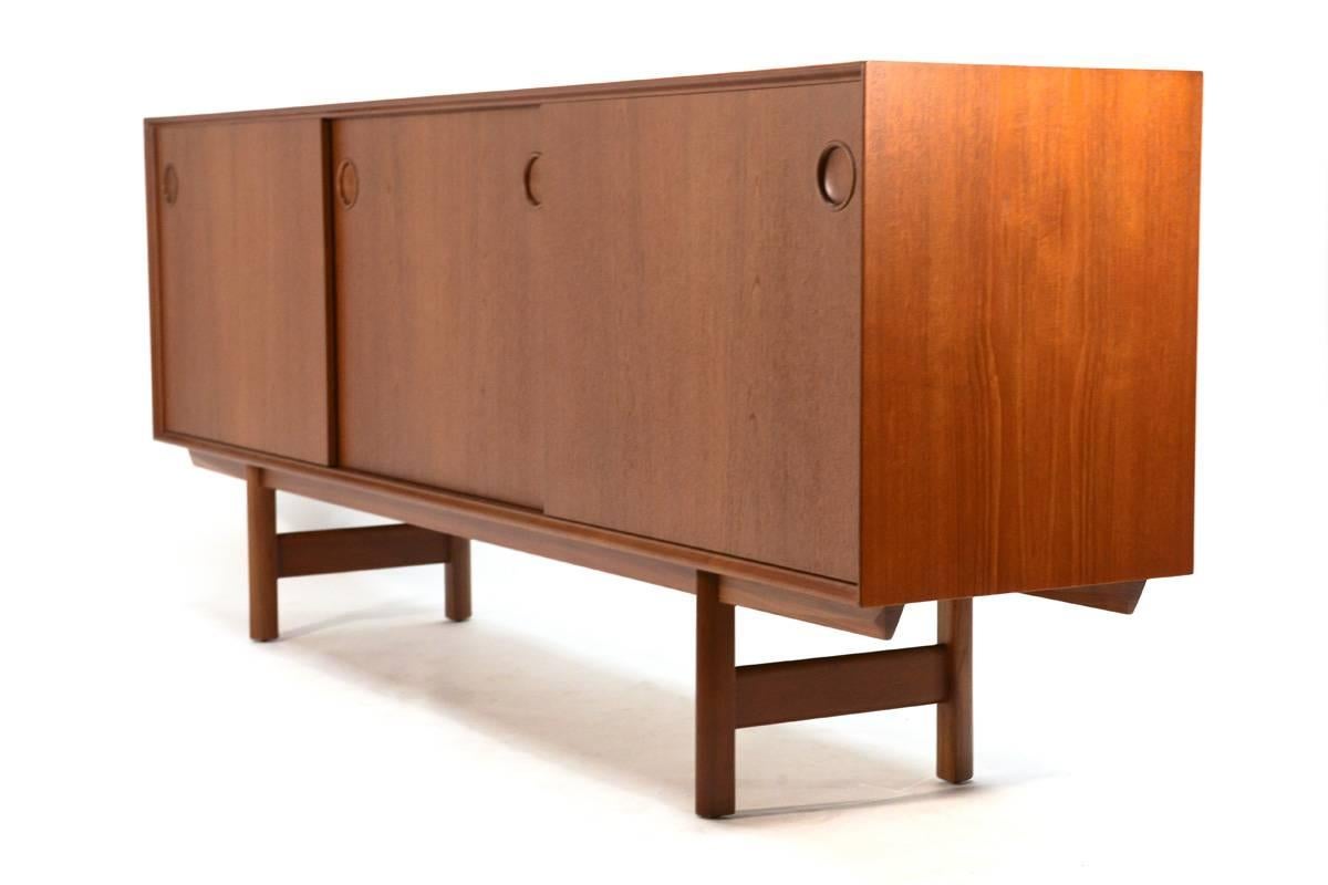 A stunning teak credenza designed by Fredrik Kayser for Gustav Bahus, circa 1952. This large credenza offers ample storage with five felt lined drawers on the right, and two adjustable shelves in both the center and left. Beautiful teak was used