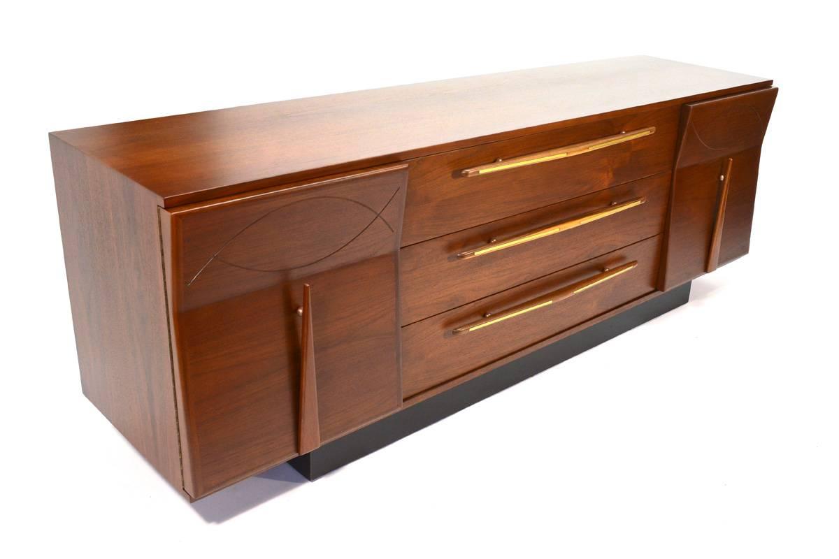 A truly stunning bedroom set produced in Mexico in the 1960's. These pieces utilize absolutely beautiful walnut, accented with brass. The angled faces with 'floating' handles is one of the more unique design aspects on these pieces. The sculptural