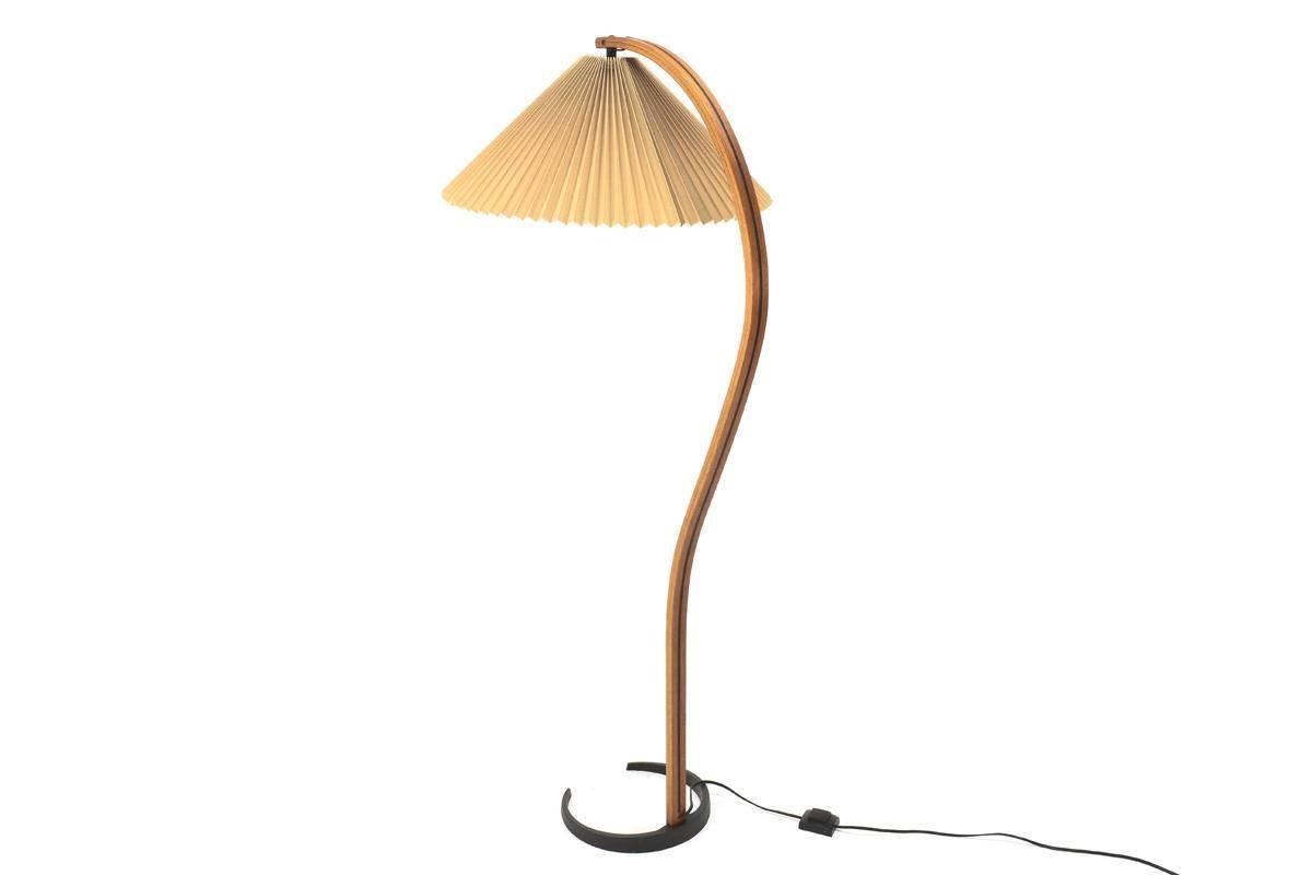 Danish bent teak floor lamp by Caprani. Retains the original pleated fabric cream shade. And sits on a black crescent cast iron base. Lamp cord is features an inline foot switch and is cleverly tucked into a groove on the back of the lamp post.