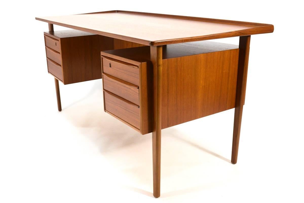 Beautiful floating top teak desk designed by Peter Løvig Nielsen in the 1960s. Offers ample storage with three drawers on each side and open shelves on the backside. There are some really nice design details on the desk like the sculpted teak lip
