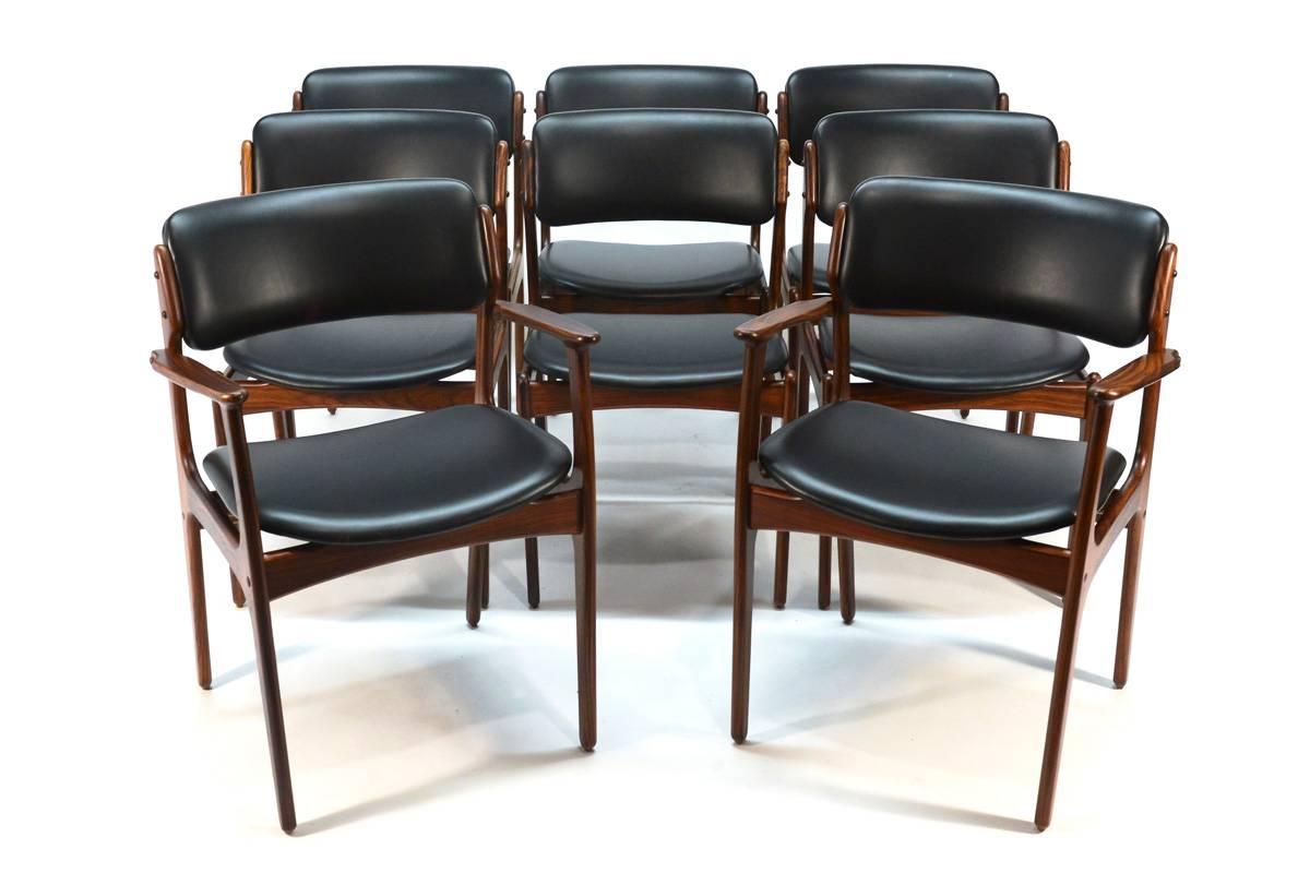 Beautiful set of eight Erik Buck model 49 rosewood dining chairs produced by O.D. Møbler. The set includes six side chairs and a pair of the desirable armchairs. These have been completely restored with new black vinyl upholstery and refinished