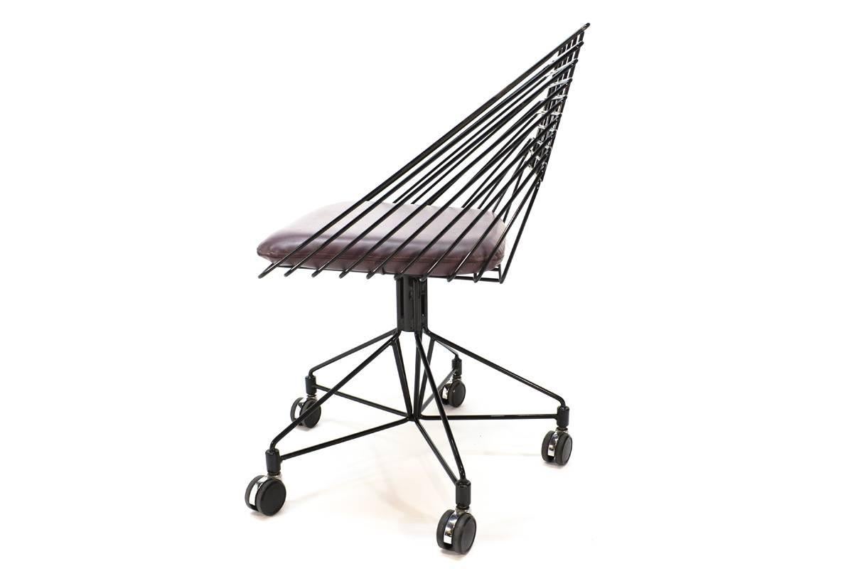 Very unique desk chair designed by Verner Panton for Fritz Hansen, produced in the 1980s. A more angular interpretation of his series of wire chairs. This example has a black frame, and retains its original deep purple or maroon seat cushion. The